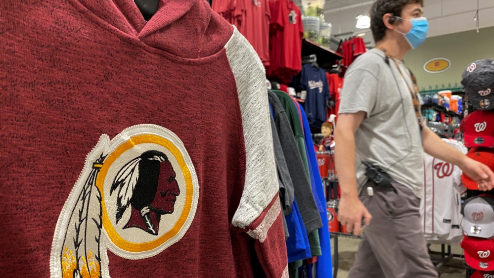 An employee passes a Washington Redskins football shirt for sale at a sporting goods store in Bailey’s Crossroads, Virginia, US