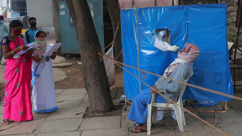 A health worker takes a nasal swab sample to test for COVID-19 in Hyderabad