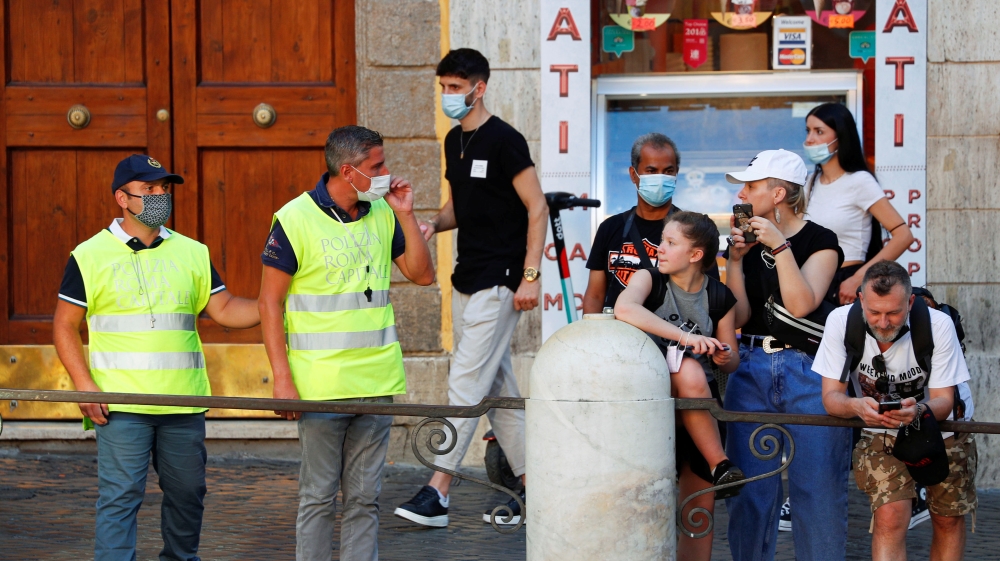 Police officers wearing yellow vests advise people on the street to wear masks following a government decree that states face coverings must be worn between 6pm and 6am near bars and pubs and in areas where gatherings are more likely