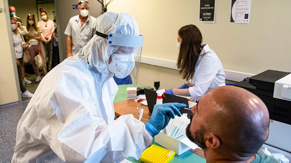 A medical worker performs a COVID-19 test at a test centre outside Moscow. Russian authorities say they are about to approve a COVID-19 vaccine, with mass vaccinations planned as early as October 2020, although clinical trials will not be complete. Scientists worldwide warn that the rush could backfire and point to ethical issues that undermine confidence in the Russian studies