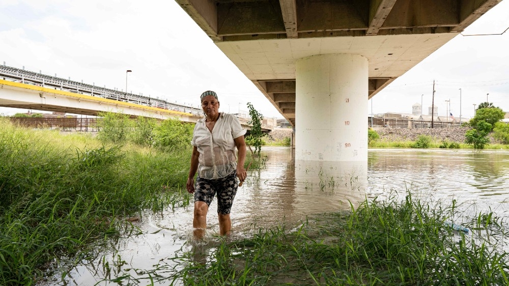 Matamoros, Mexico, August 1, 2020, a resident of the refugee camp inspects the sandbag wall that was laid to protect the camp from the expanding river banks