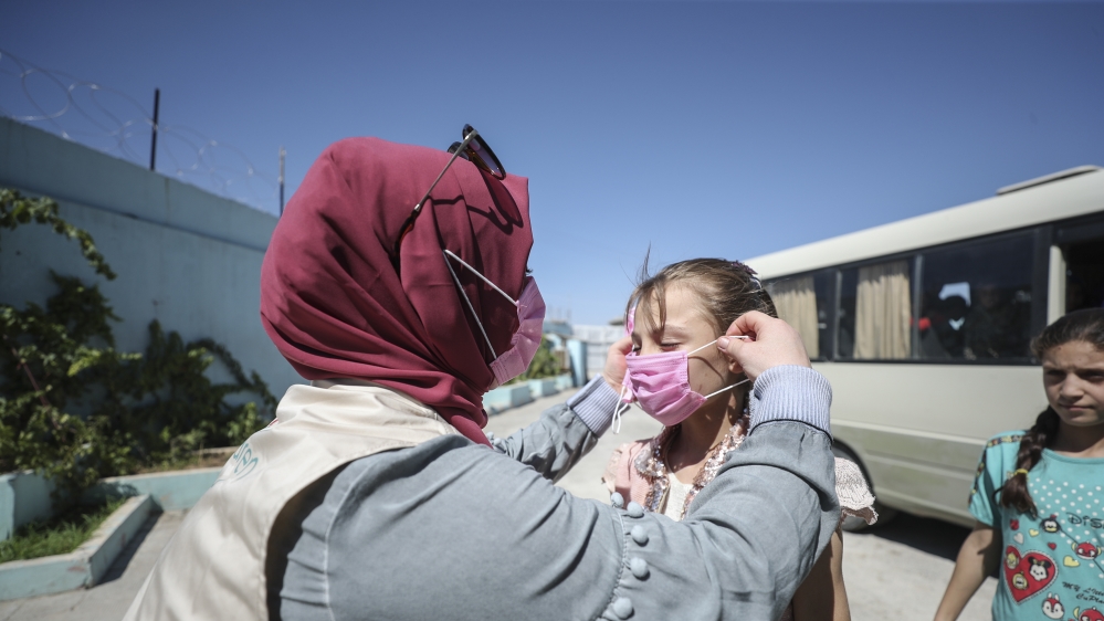 A girl is given a mask at a refugee camp located in Syria’s Jarablus