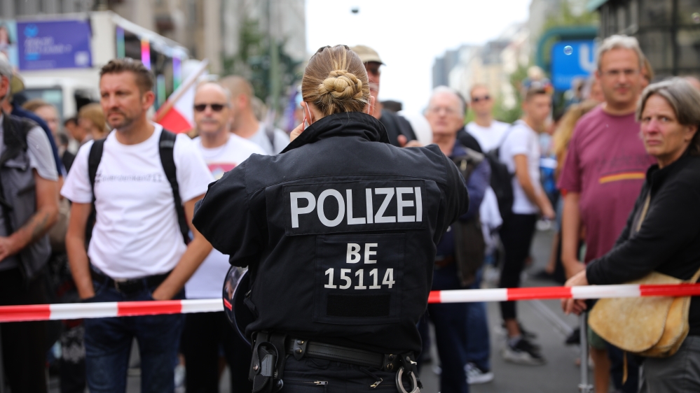 A police officer stands in front of protesters as they march against coronavirus-related restrictions and government policy on August 29