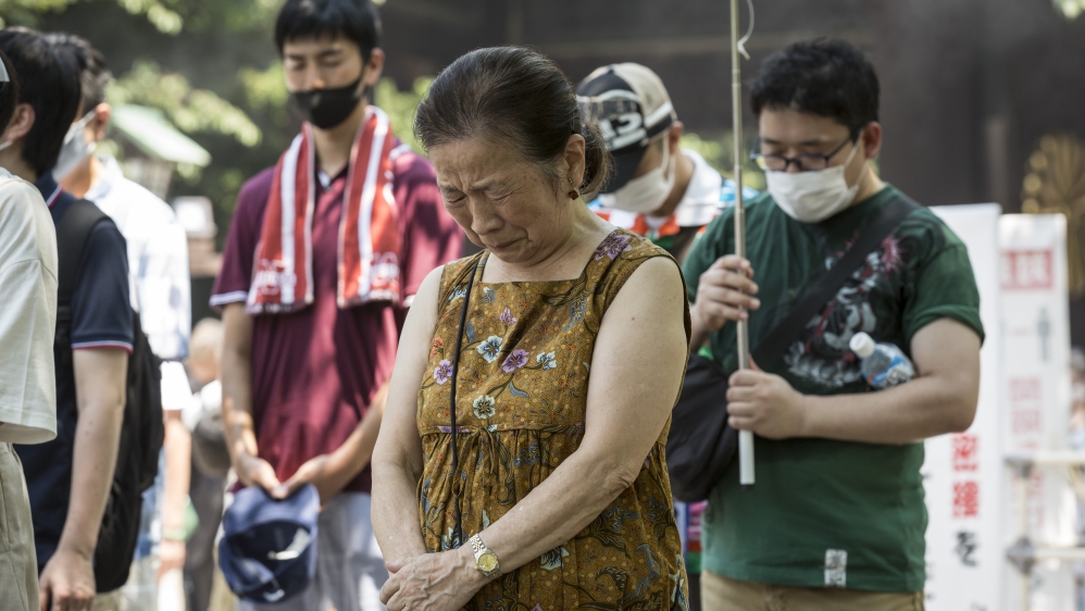 A woman cries during a minute of silence at Yasukuni Shrine on Saturday