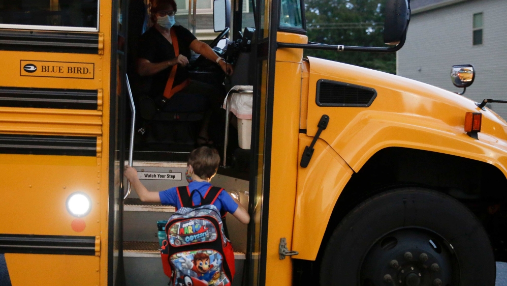 Paul Adamus, seven, climbing the stairs of the school bus on the first day of school on August 3, 2020, in Dallas, Georgia