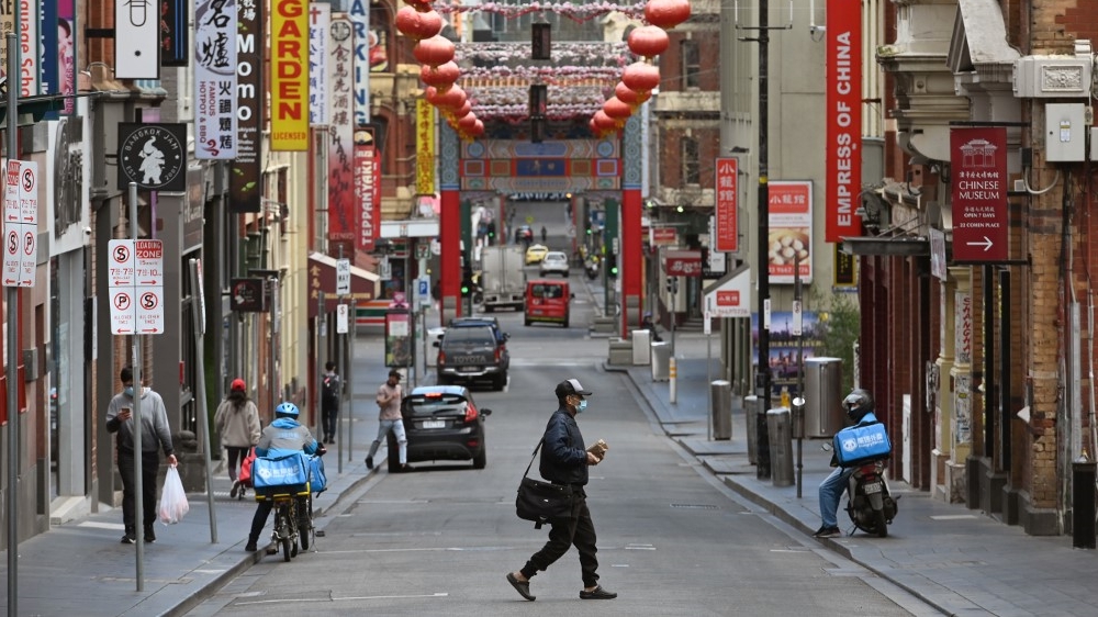 A man wearing a face mask crosses a quiet road in Melbourne’s Chinatown area on August 13, 2020