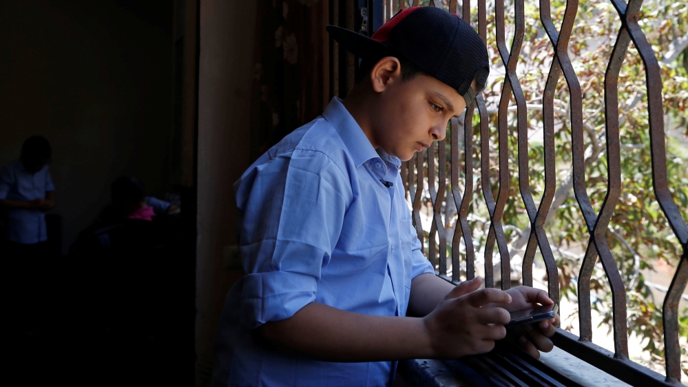 Abdulrahman al-Shantti uses a mobile phone as he stands by a window in his family home in Gaza City