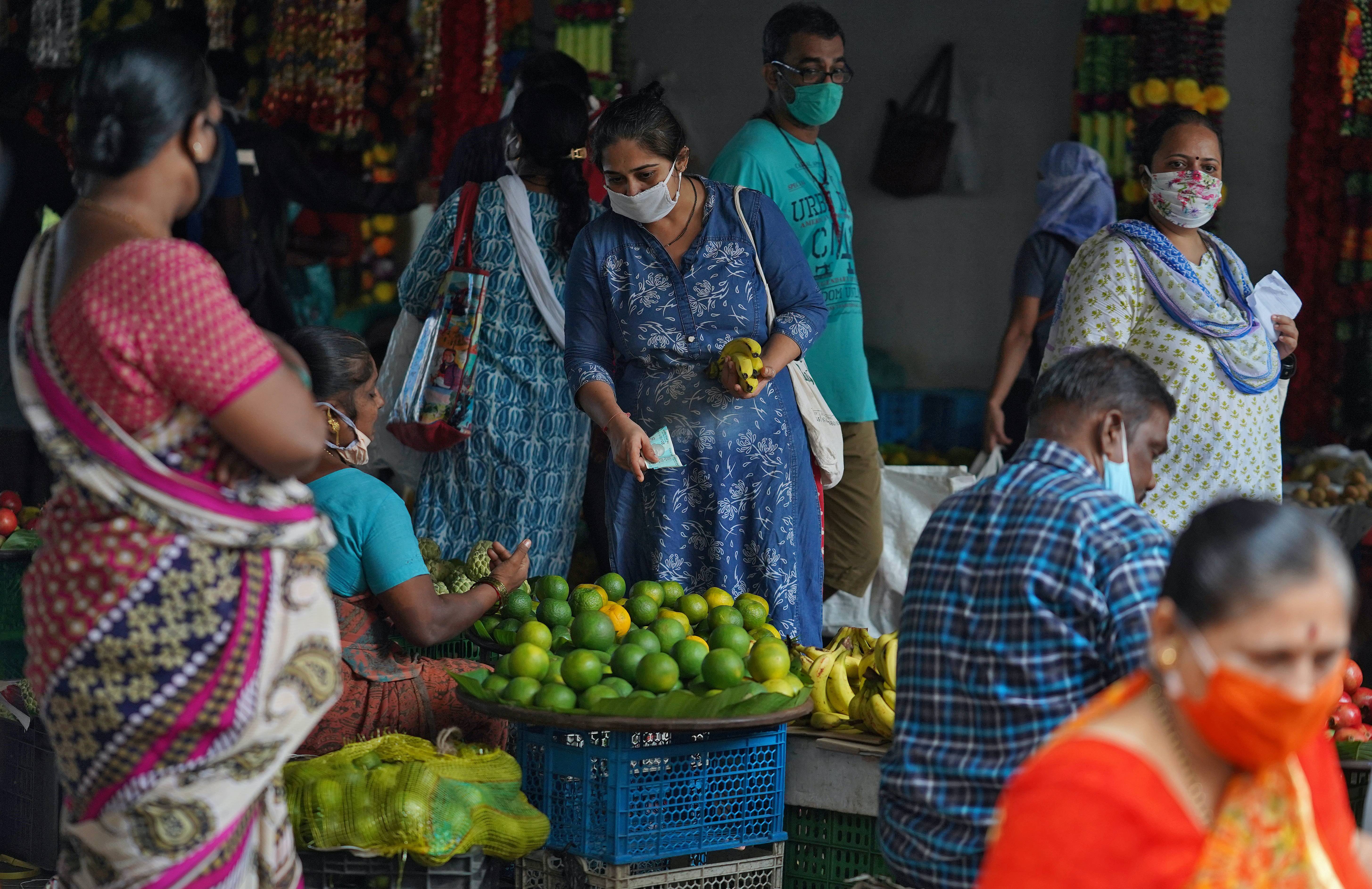 A woman wearing a face mask buys fruit in a market, amid the spread of the coronavirus in Mumbai, India