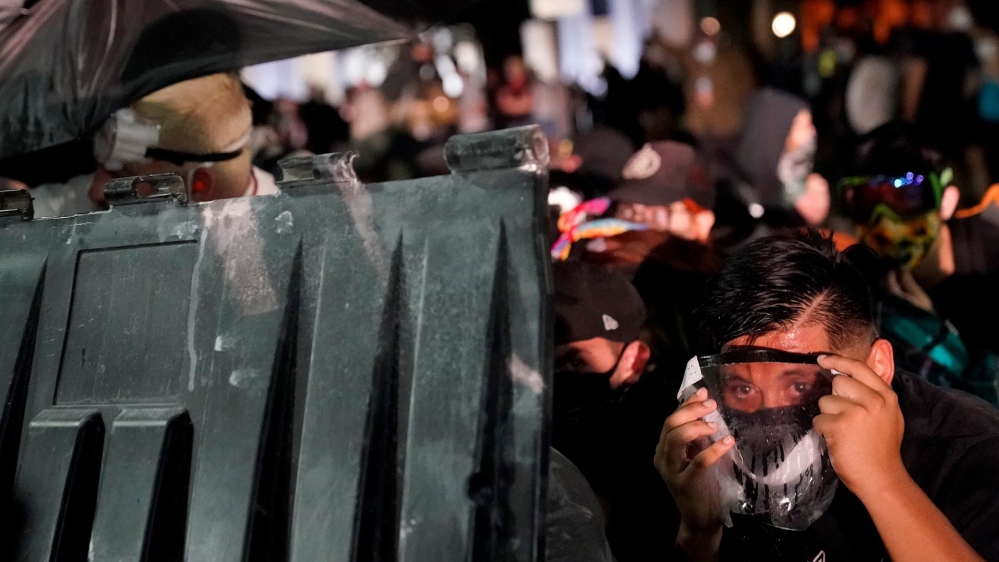 A protester takes cover during clashes outside the Kenosha County Courthouse late on Tuesday during protests following the police shooting of Jacob Blake two days earlier