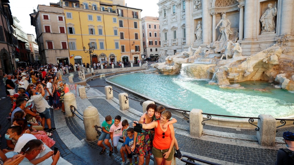 People without face masks take selfies in front of the Trevi Fountain following a government decree that states face coverings must be worn after 6pm in areas where gatherings are more likely