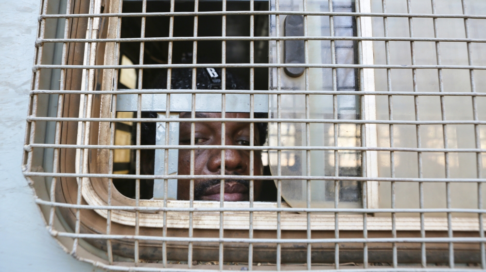Zimbabwe Journalist Hopwell Chin''ono is seen through the window of a prison truck upon his arrival at the magistrates courts for his bail ruling in Harare, Monday, Aug, 24, 2020. A magistrate has deni