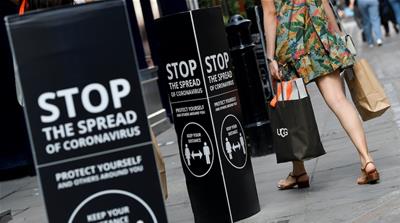 Shoppers walk past social-distancing signs at the Covent Garden shopping and dining district in London, amid the spread of the coronavirus disease
