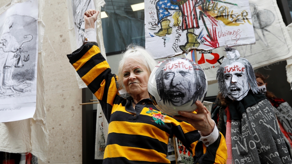 Fashion designer Dame Vivienne Westwood gestures as she holds a ball with a word ‘justice’ written on it outside Assange’s court hearing in London