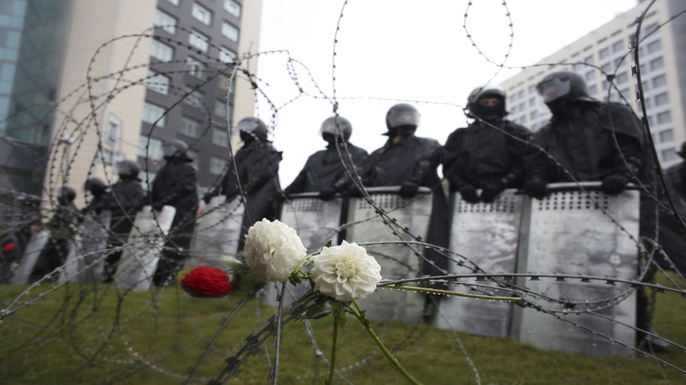 Flowers lie on a barbed-wire fence in front of a police line towards the Independence Palace, residence of the President Alexander Lukashenko [TUT.BY via AP]