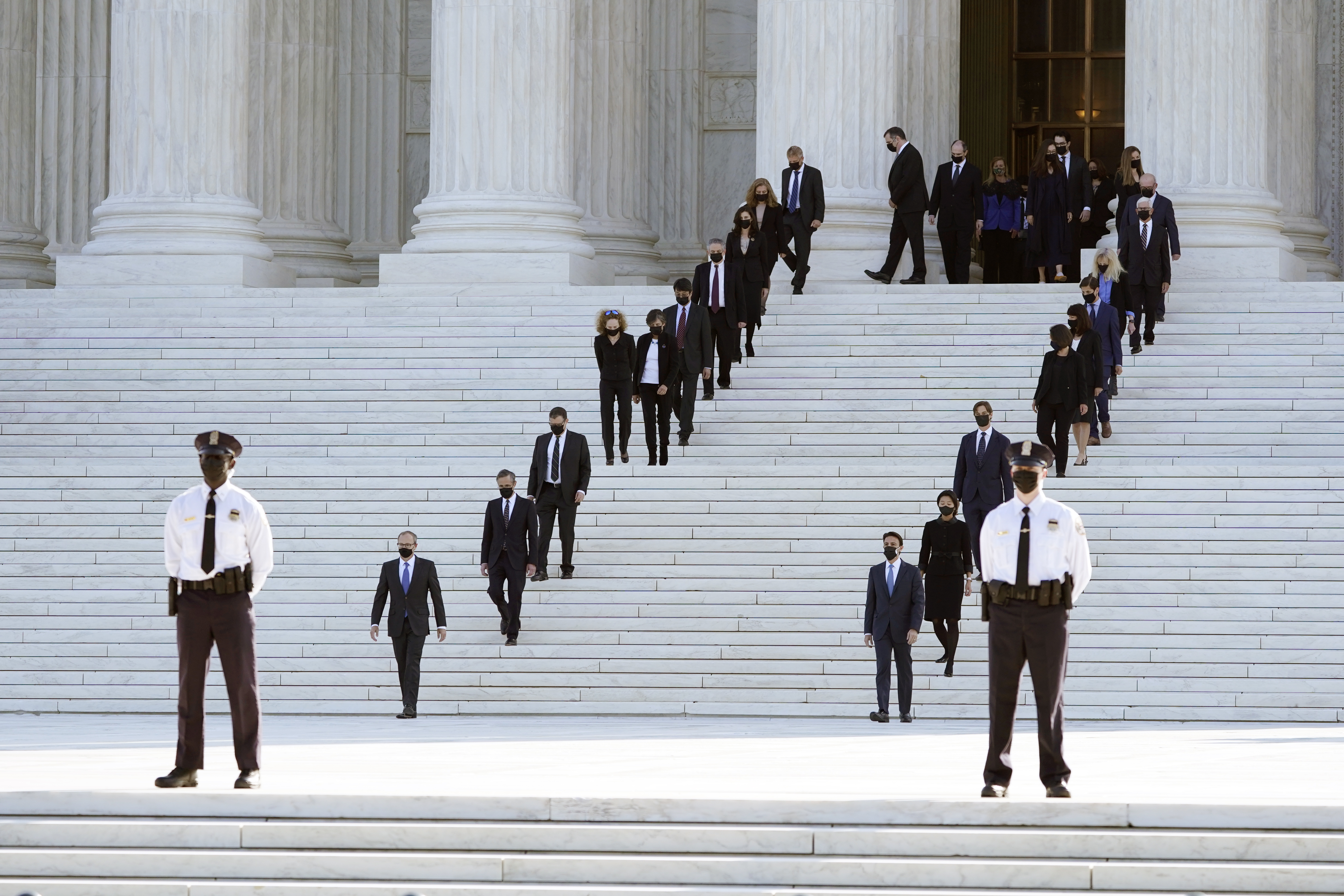 Former law clerks walk out and stand for the coffin of Justice Ruth Bader Ginsburg at the Supreme Court
