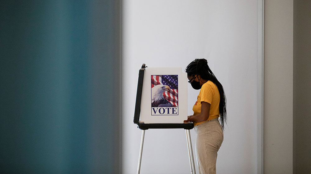 A woman casts her ballots for the upcoming presidential elections as early voting begins Michigan