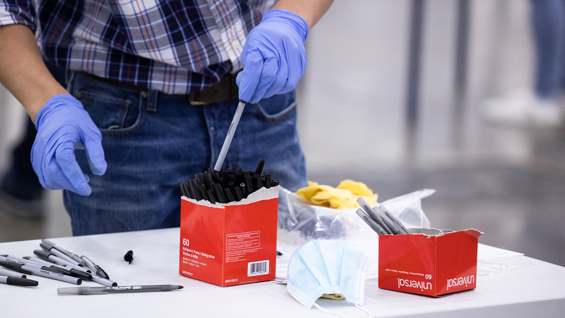 A poll worker wears gloves as a protective measure due to the coronavirus while sorting pens at a polling station in Louisville, Kentucky on June 23, 2020