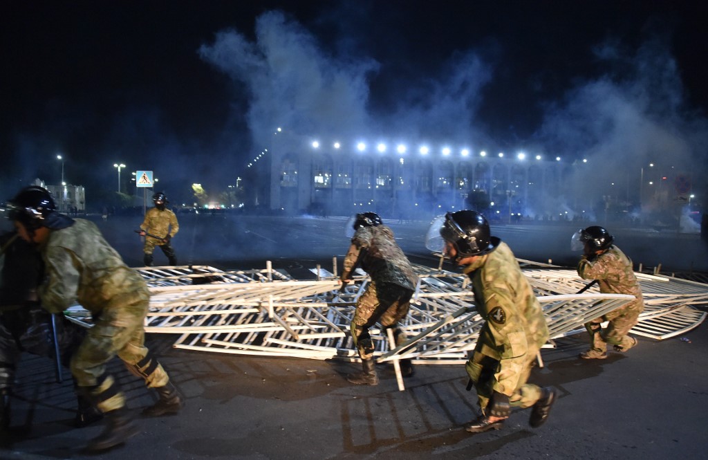 Law enforcement officers remove a barricade set up by protesters during a rally against the results of a parliamentary vote in Bishkek on Monday night [Vyacheslav Oseledko/ AFP)