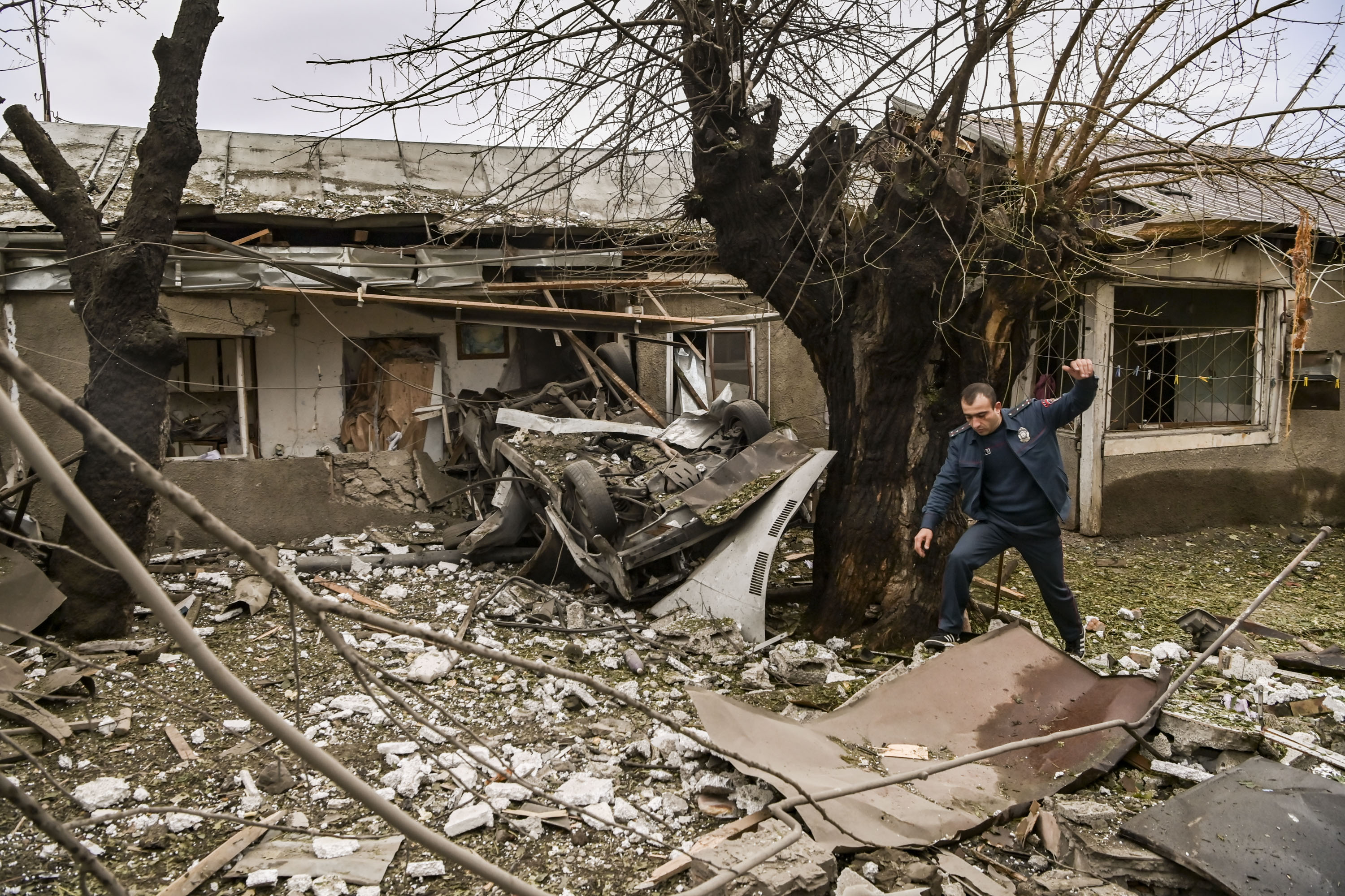A police officer steps over debris in the yard of a destroyed house after shelling in the breakaway Nagorno-Karabakh region’s main city of Stepanakert