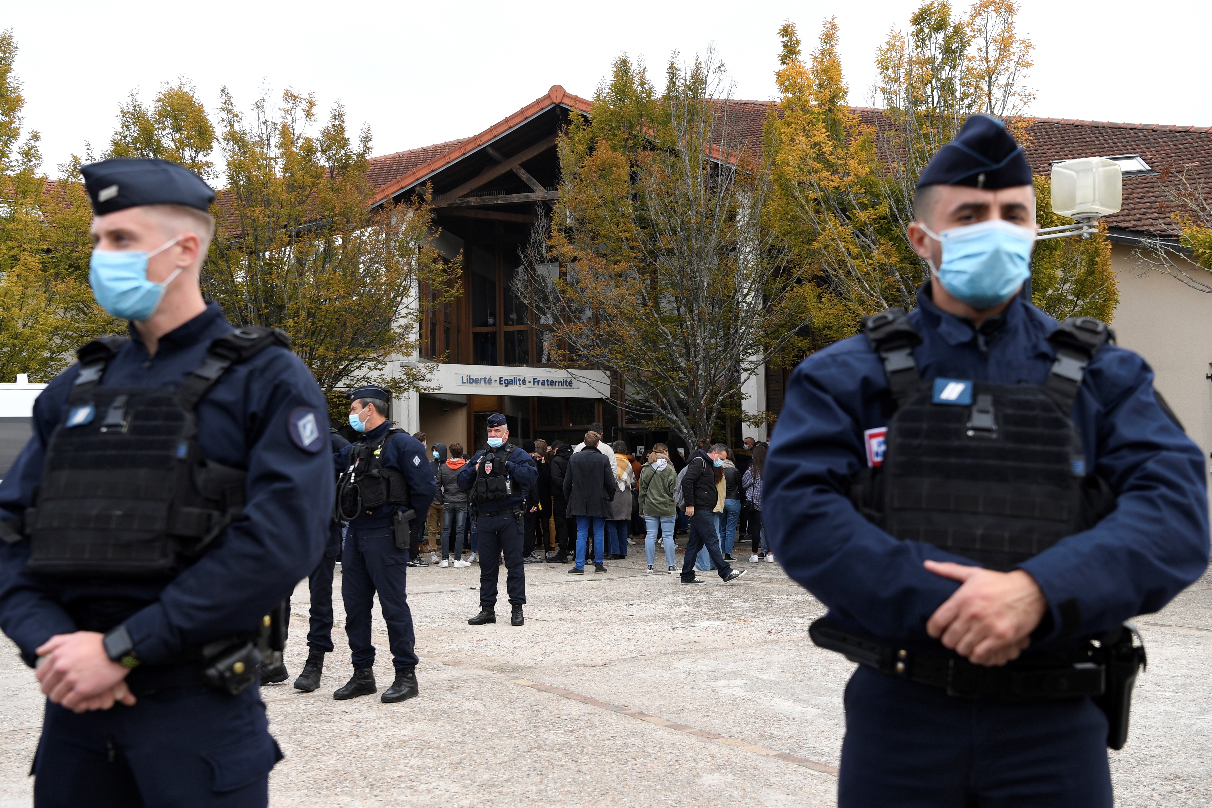 French police officers stand guard outside the school in the suburbs of Paris where Samuel Paty was brutally killed as he left work on Friday