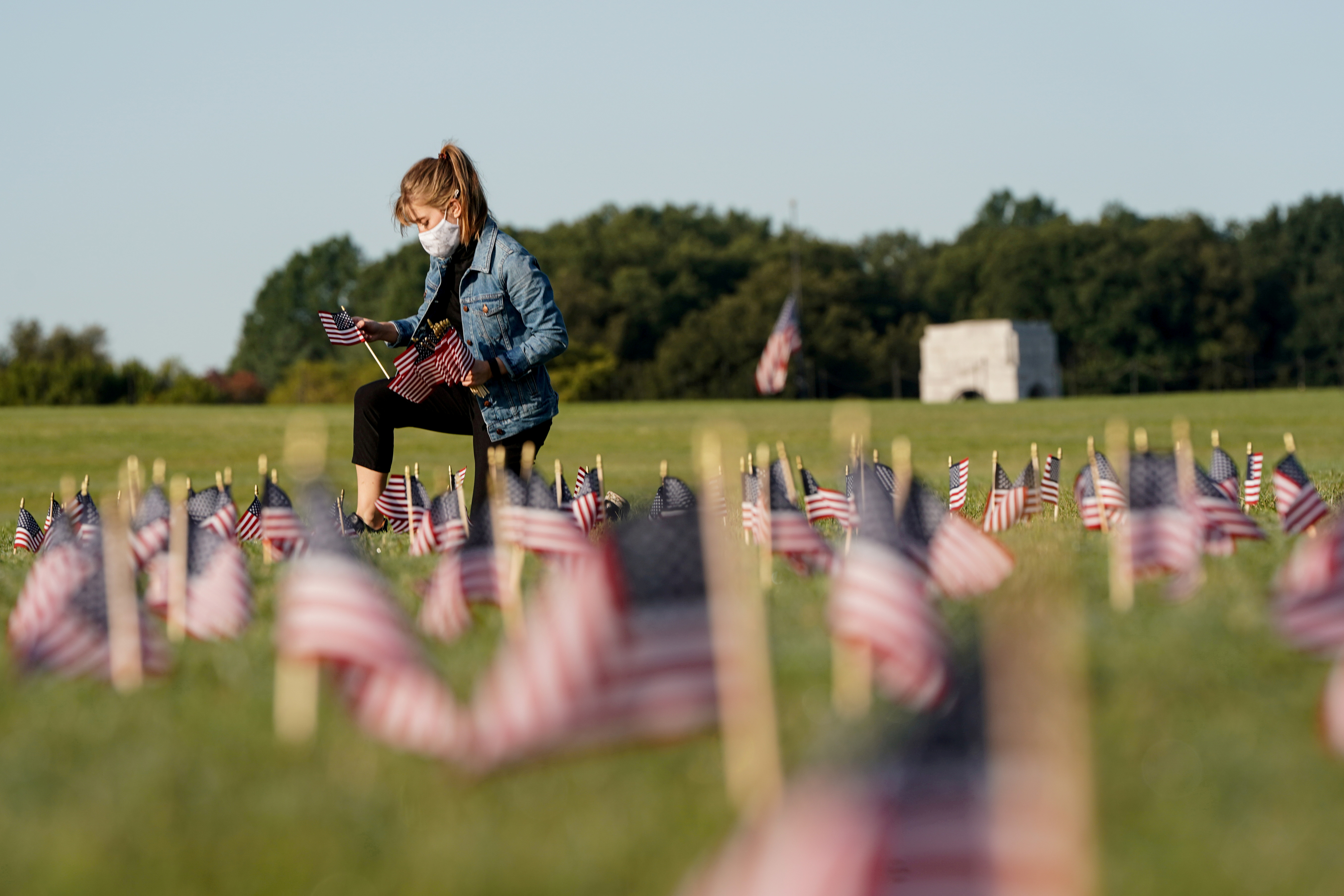 A volunteer places American flags representing the 215,000 lives lost in the United States in the coronavirus disease pandemic on the National Mall in Washington, US