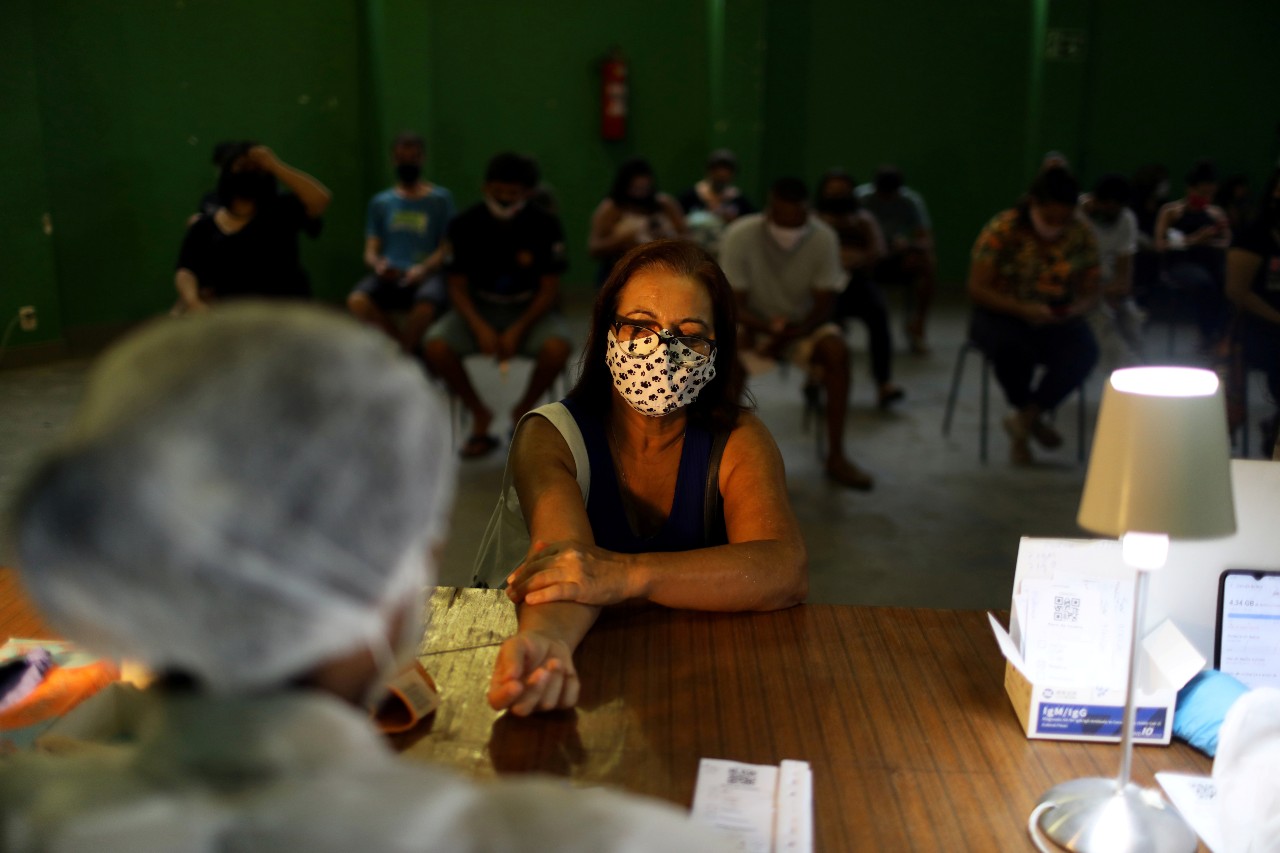 A nurse in Rio de Janeiro takes a blood sample from a woman for a COVID-19 test with the help of ‘Dados do Bem’ app, developed by doctors and scientists to use data information to analyze the evolution of population immunity