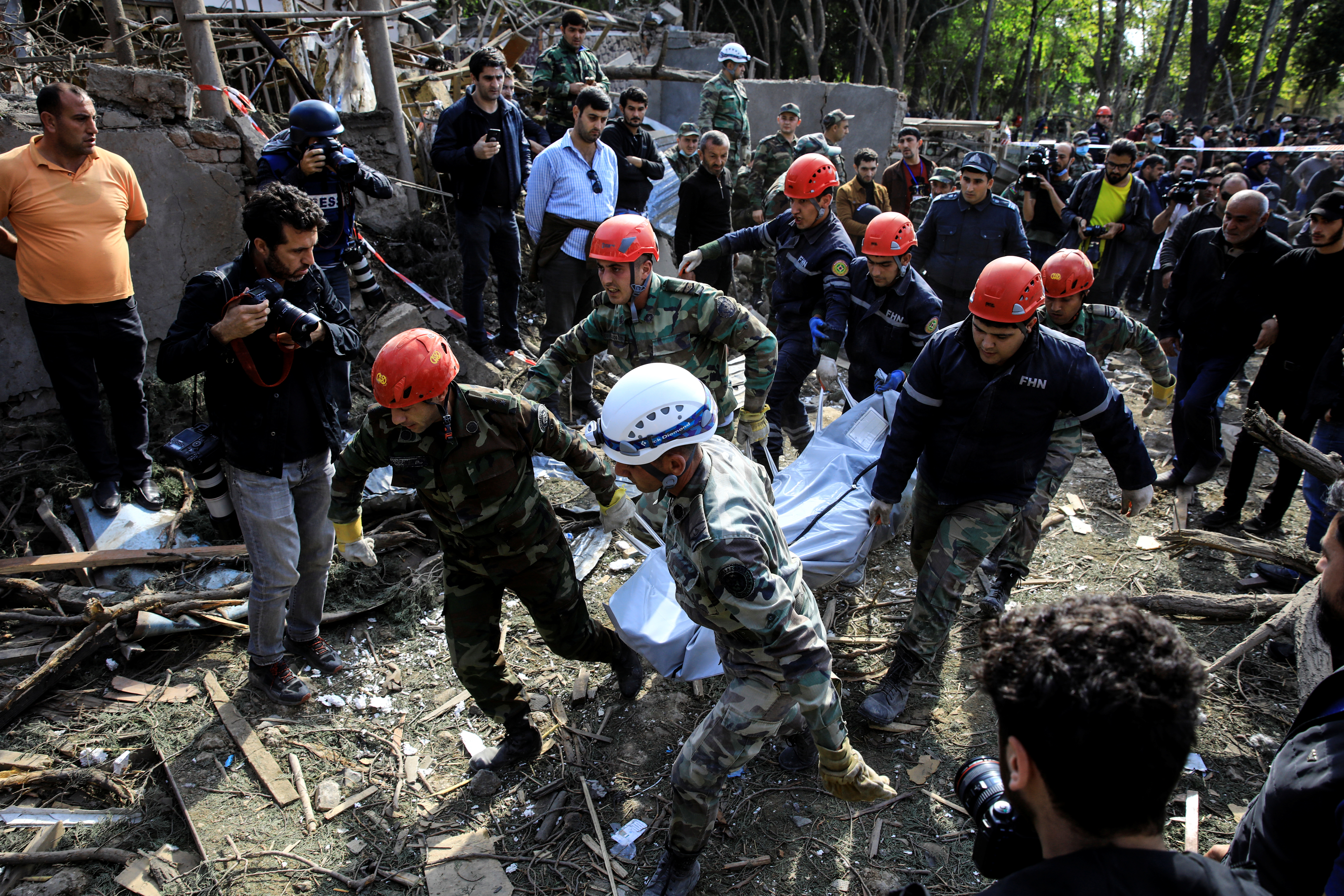 Search and rescue teams carry the body of a victim away from the blast site hit by a rocket during the fighting over the breakaway region of Nagorno-Karabakh in the city of Ganja, Azerbaijan October 11, 2020