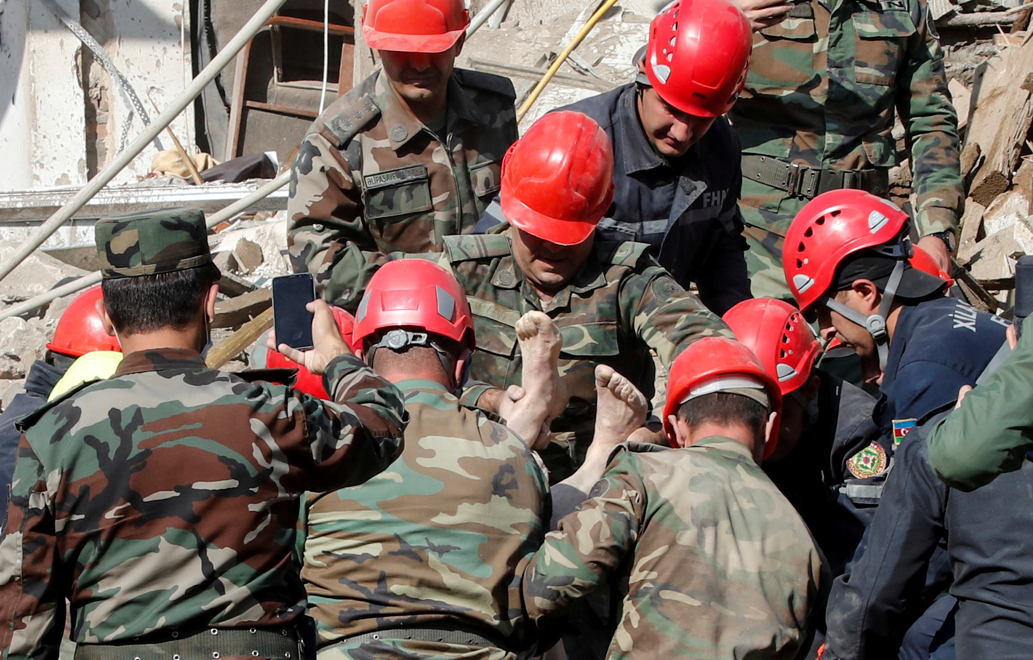 Search and rescue teams carry the body of a victim away from the blast site hit by a rocket during the fighting over the breakaway region of Nagorno-Karabakh in the city of Ganja, Azerbaijan