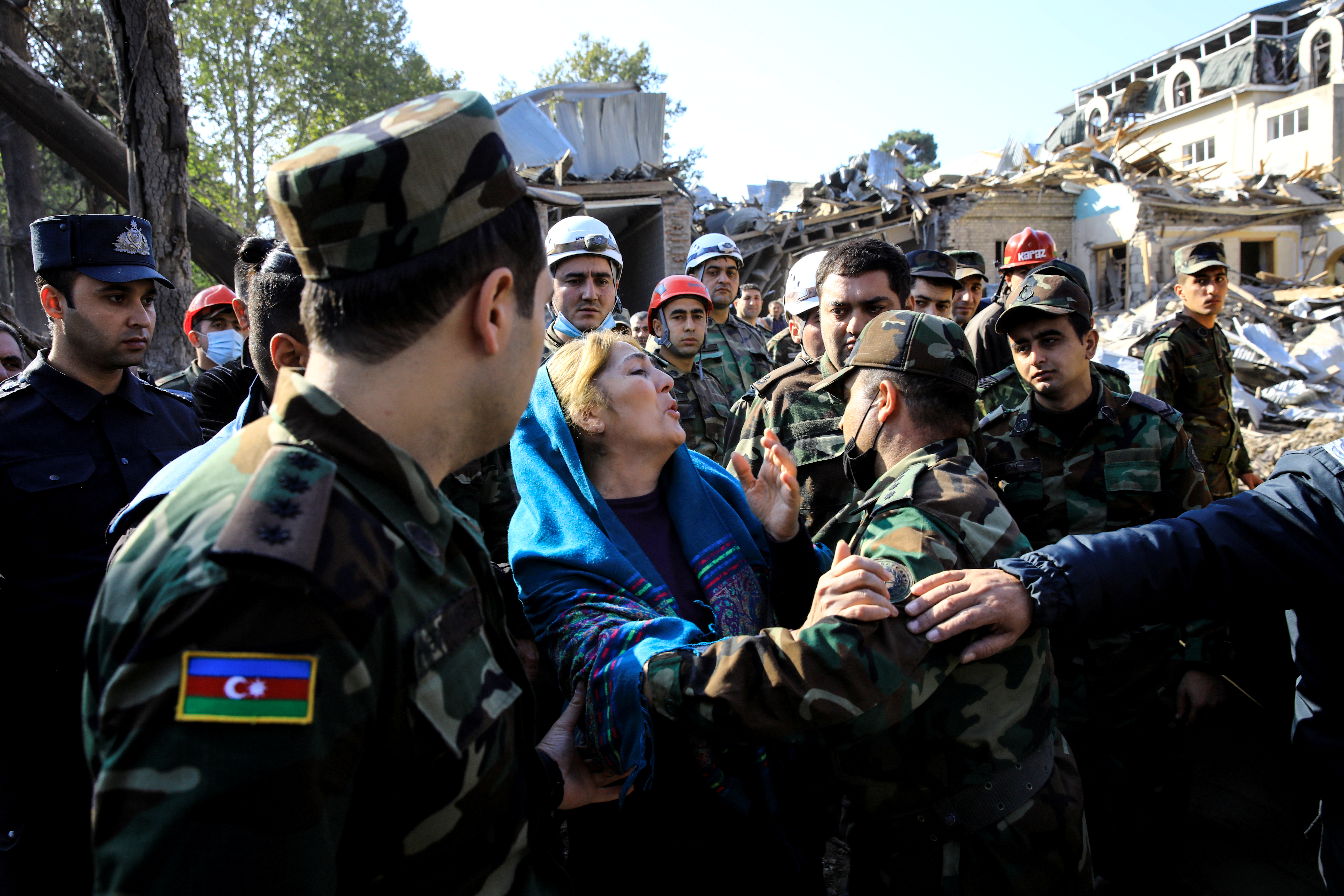 A woman waits for her relatives to be rescued as search and rescue teams work on the blast site hit by a rocket during the fighting over the region of Nagorno-Karabakh