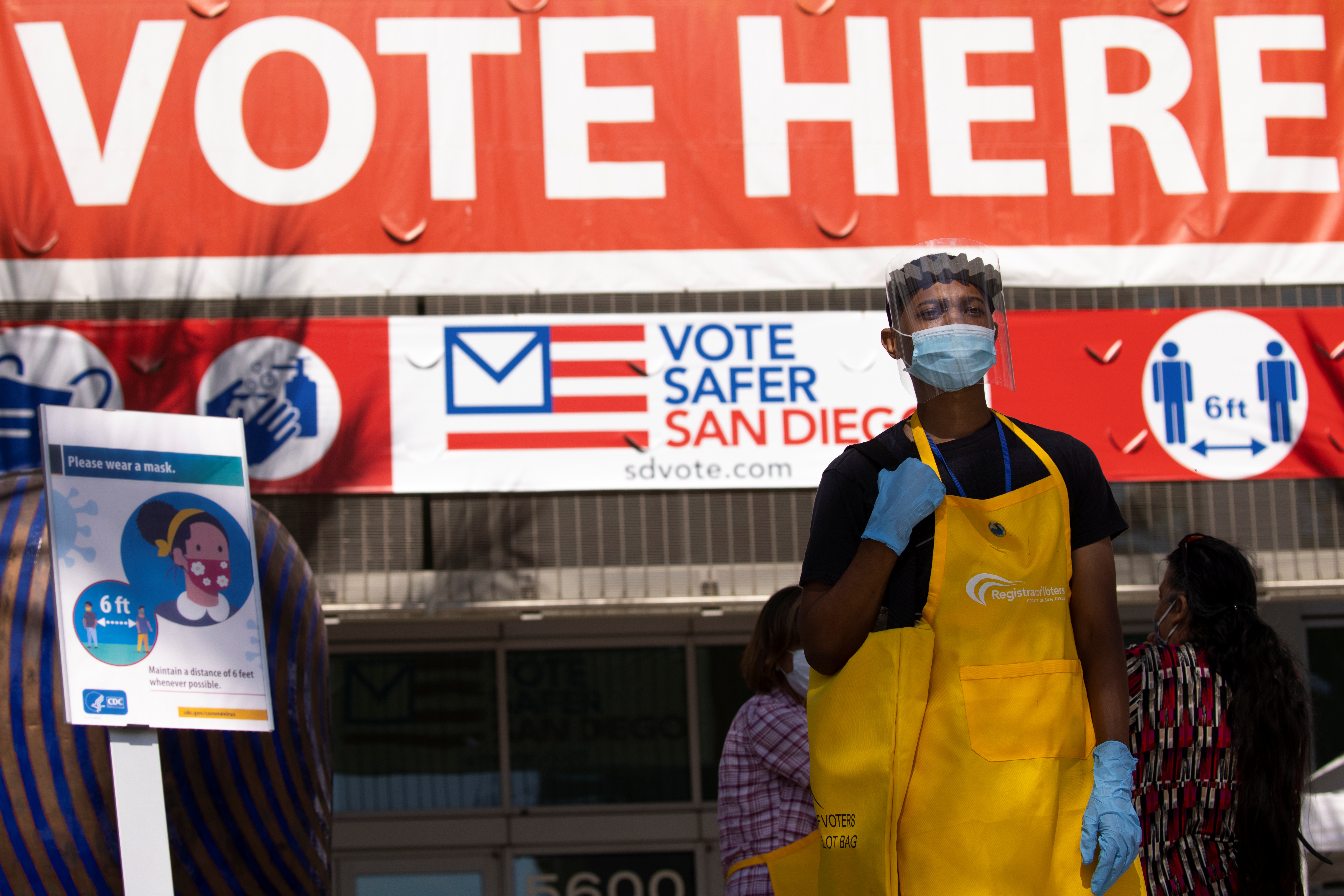 An election worker collects mail-in ballots and guides voters at the entrance to the Registrar of Voters building in San Diego, California, on October 19, 2020