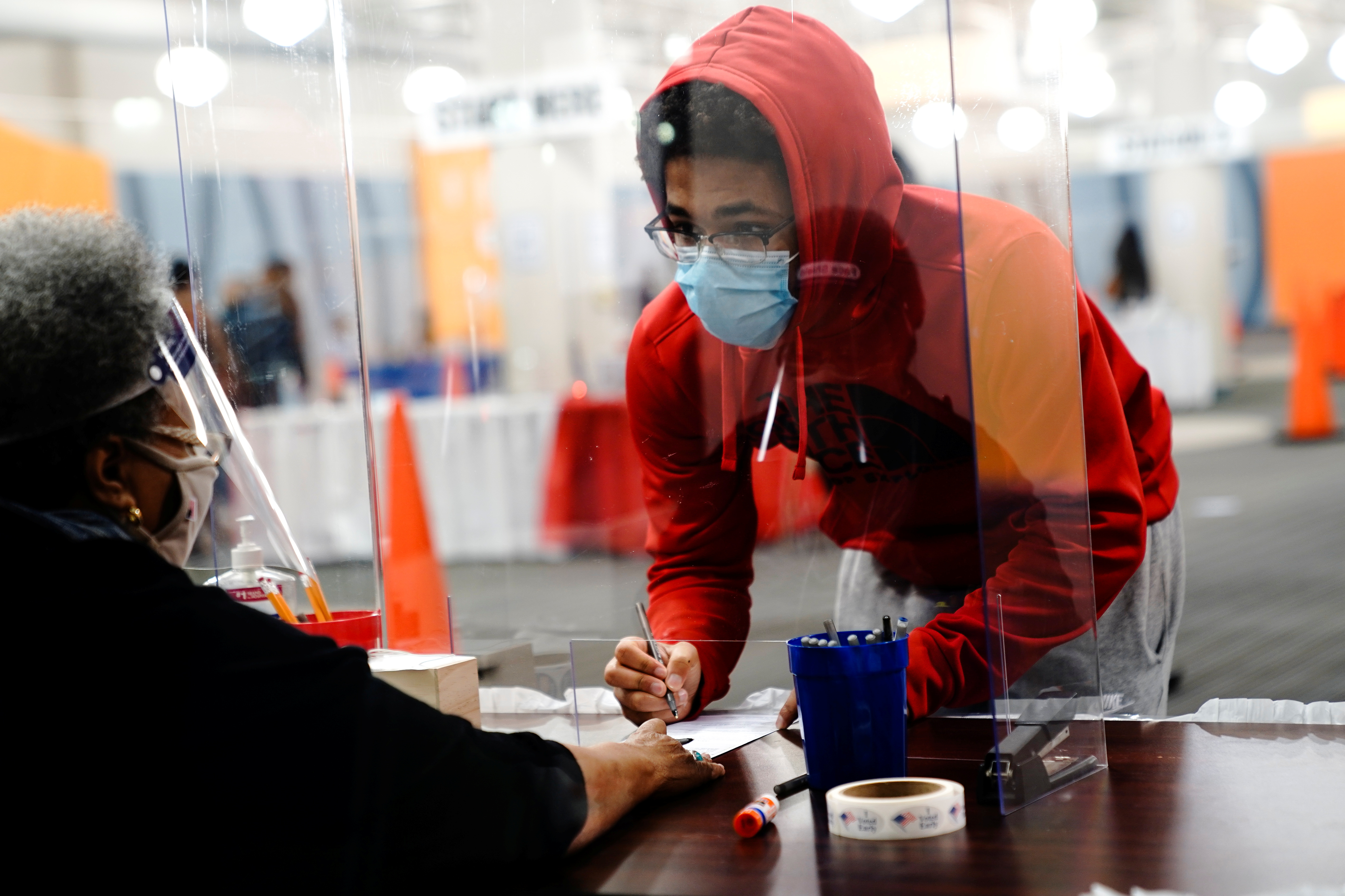 A young voter fills out a ballot with assistance from a poll worker at a polling station in Milwaukee on the first day of in-person voting in Wisconsin on October 20, 2020