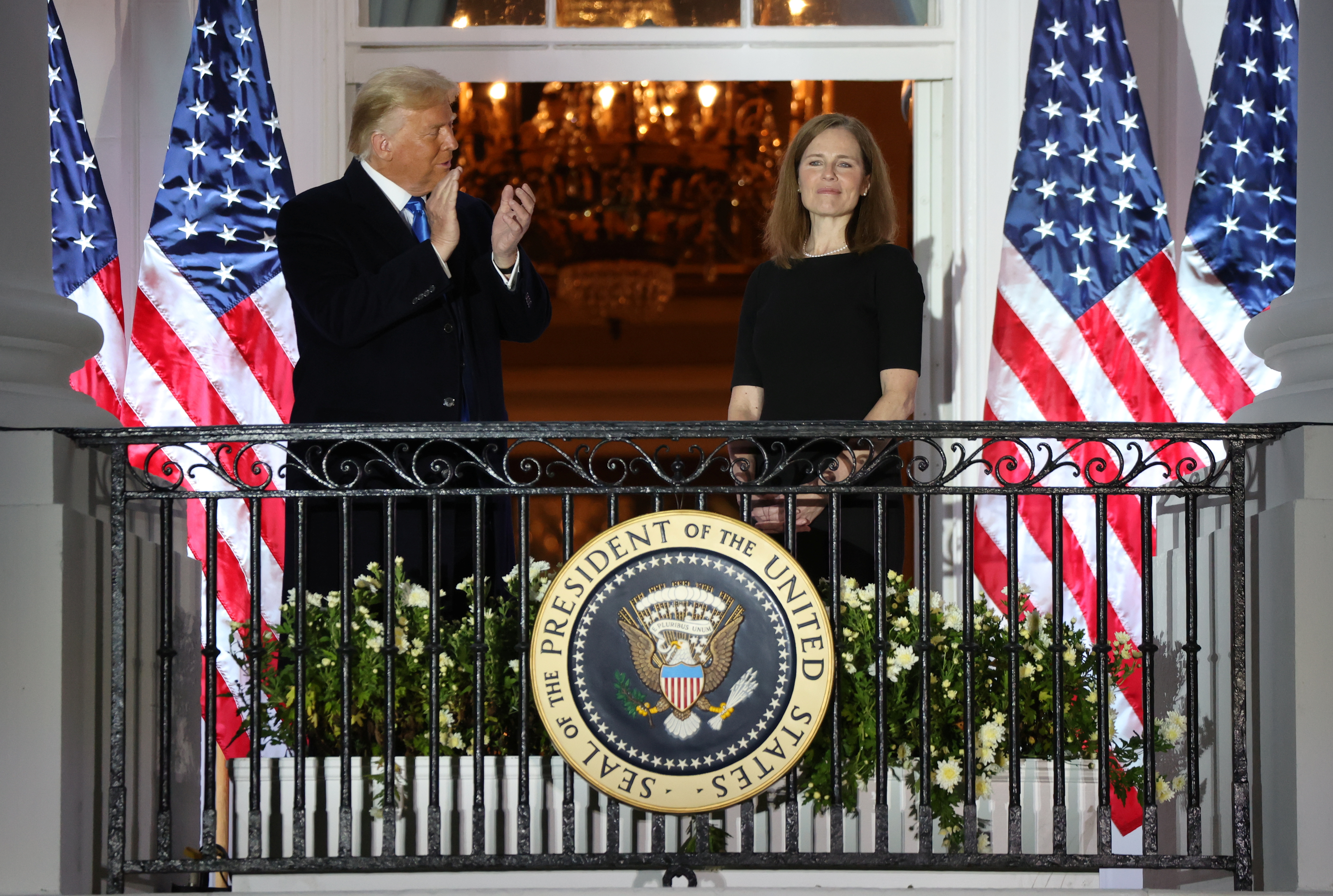 President Donald Trump applauds Amy Coney Barrett after she took her oath of office and was sworn in to serve on the court with just a week before the presidential election