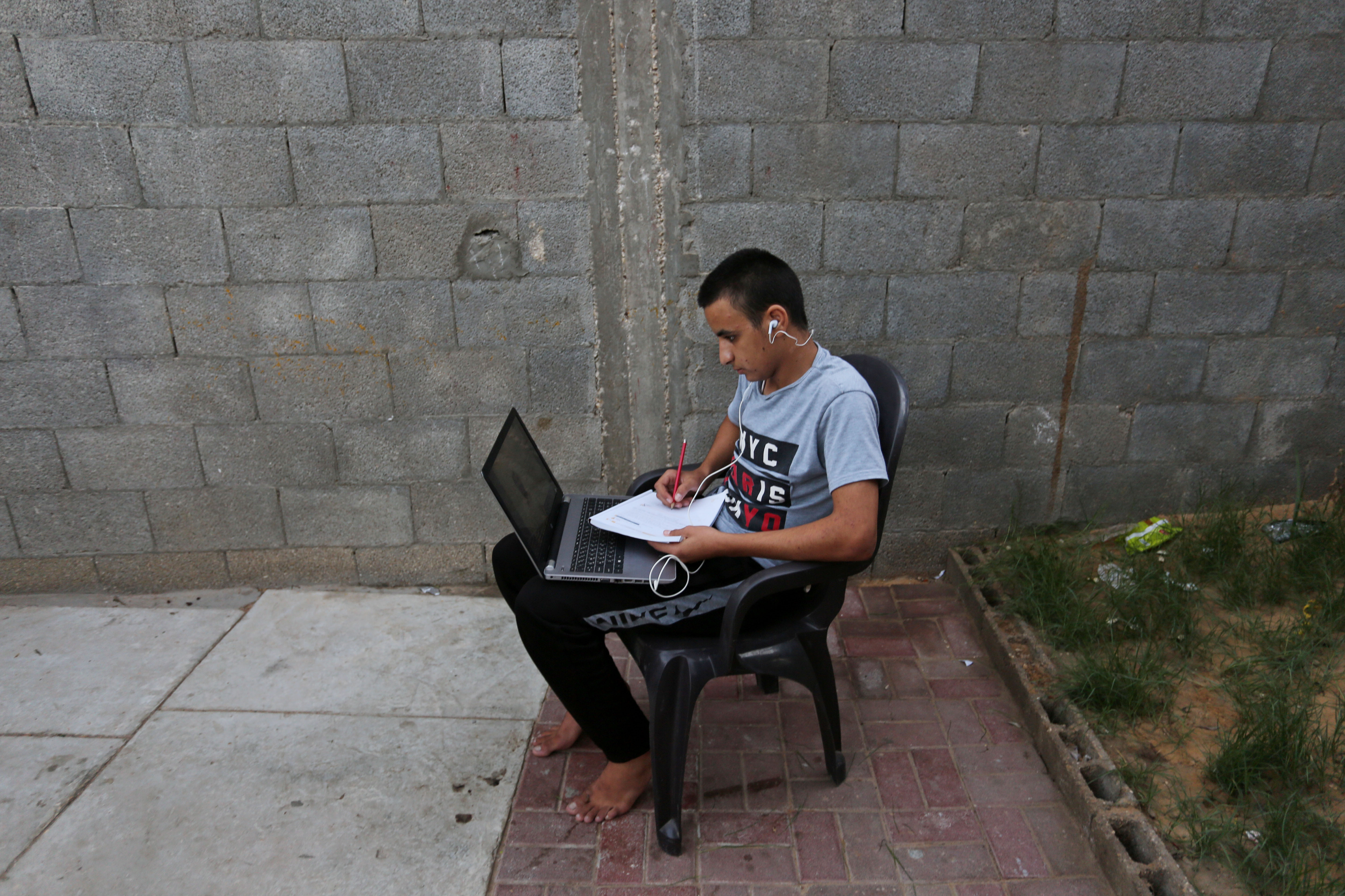 Bahaa Elian,16, attends class remotely from his garden in Deir Al-Balah