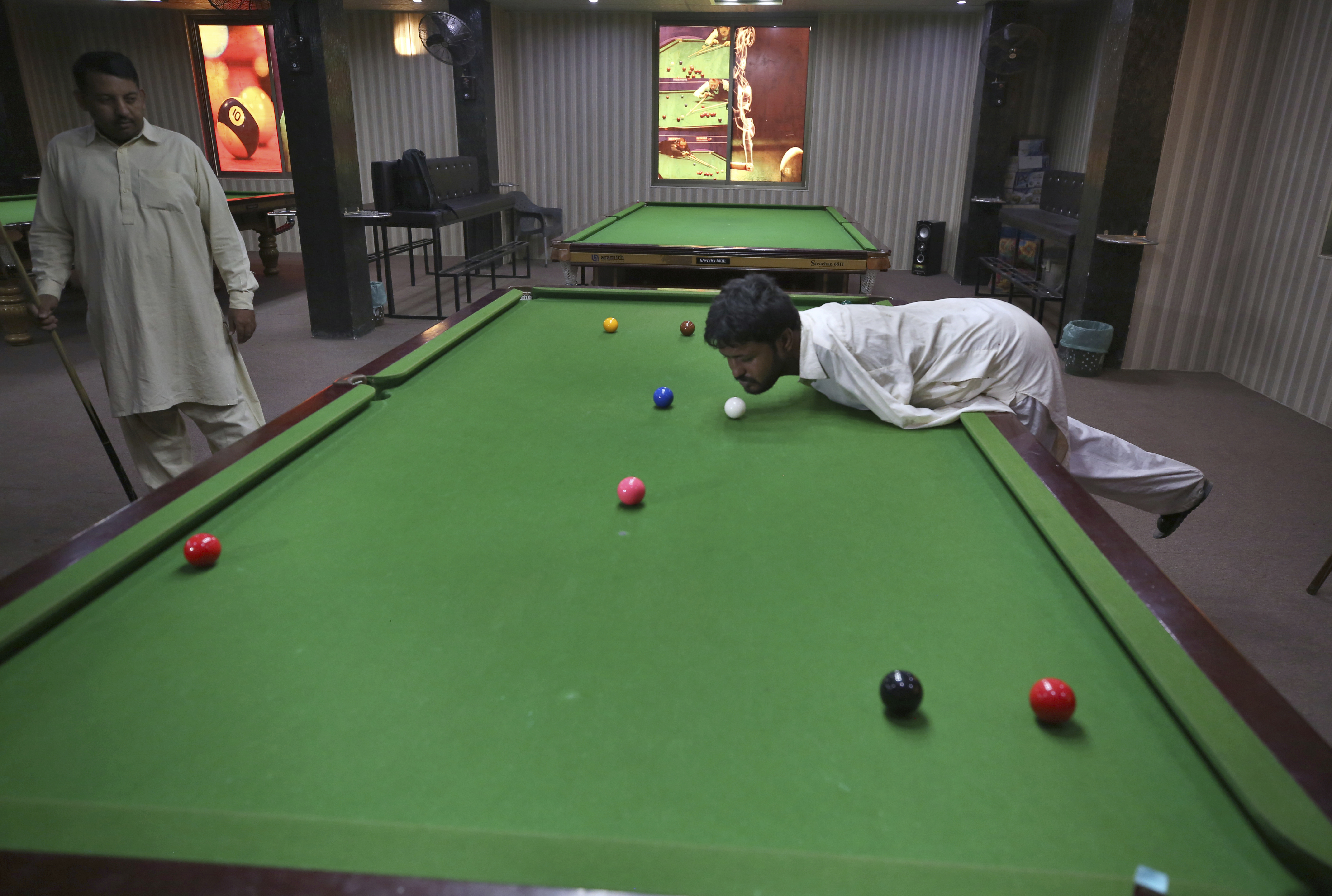 Ikram plays snooker with his chin at a local snooker club in Samundri, Pakistan