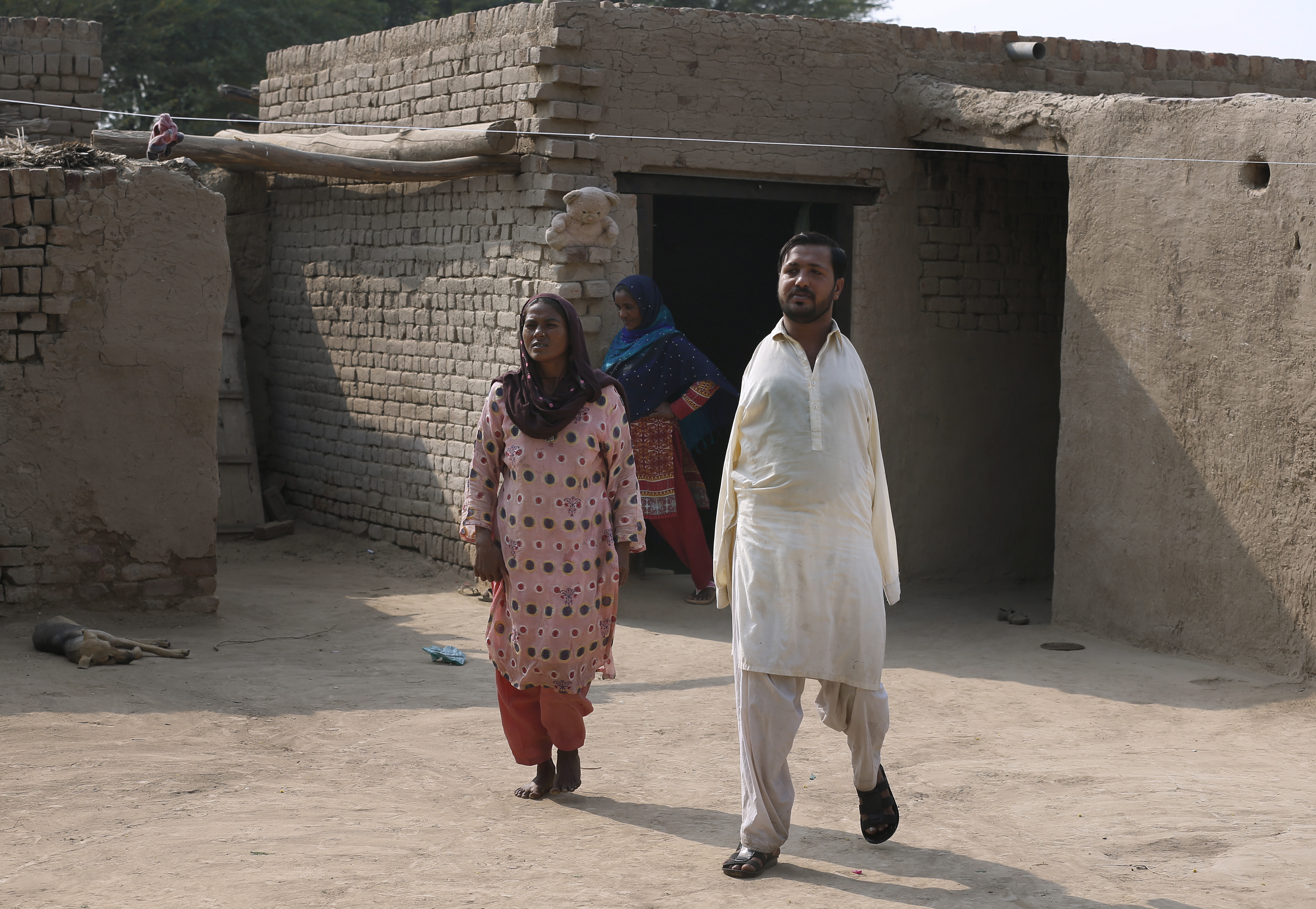 Ikram, right, walks with his mother Rizia Bibi at home in a village near Samundri, Pakistan