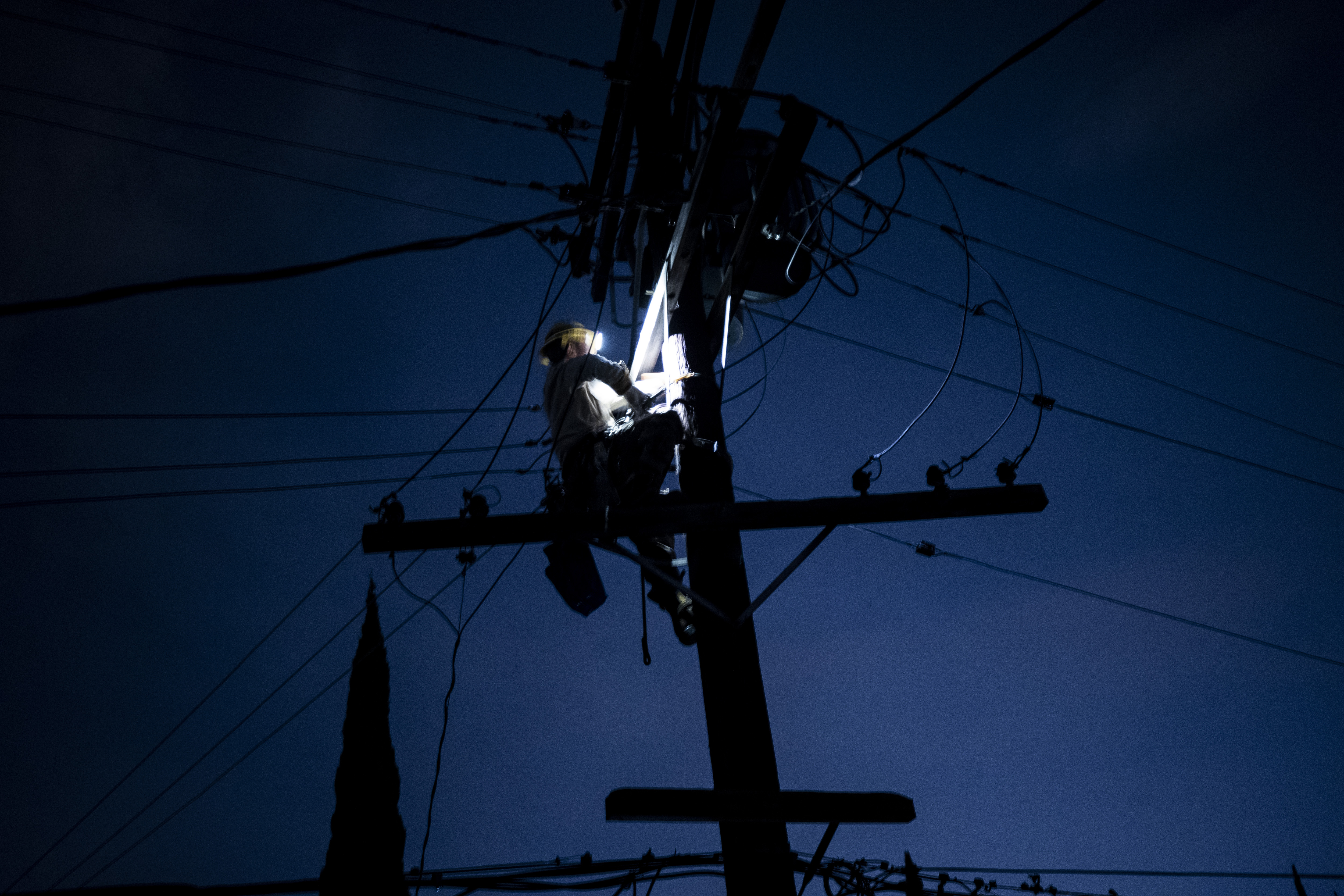 In this file photo from September, a technician works on an electric pole during a power cut amid a heatwave in Los Angeles