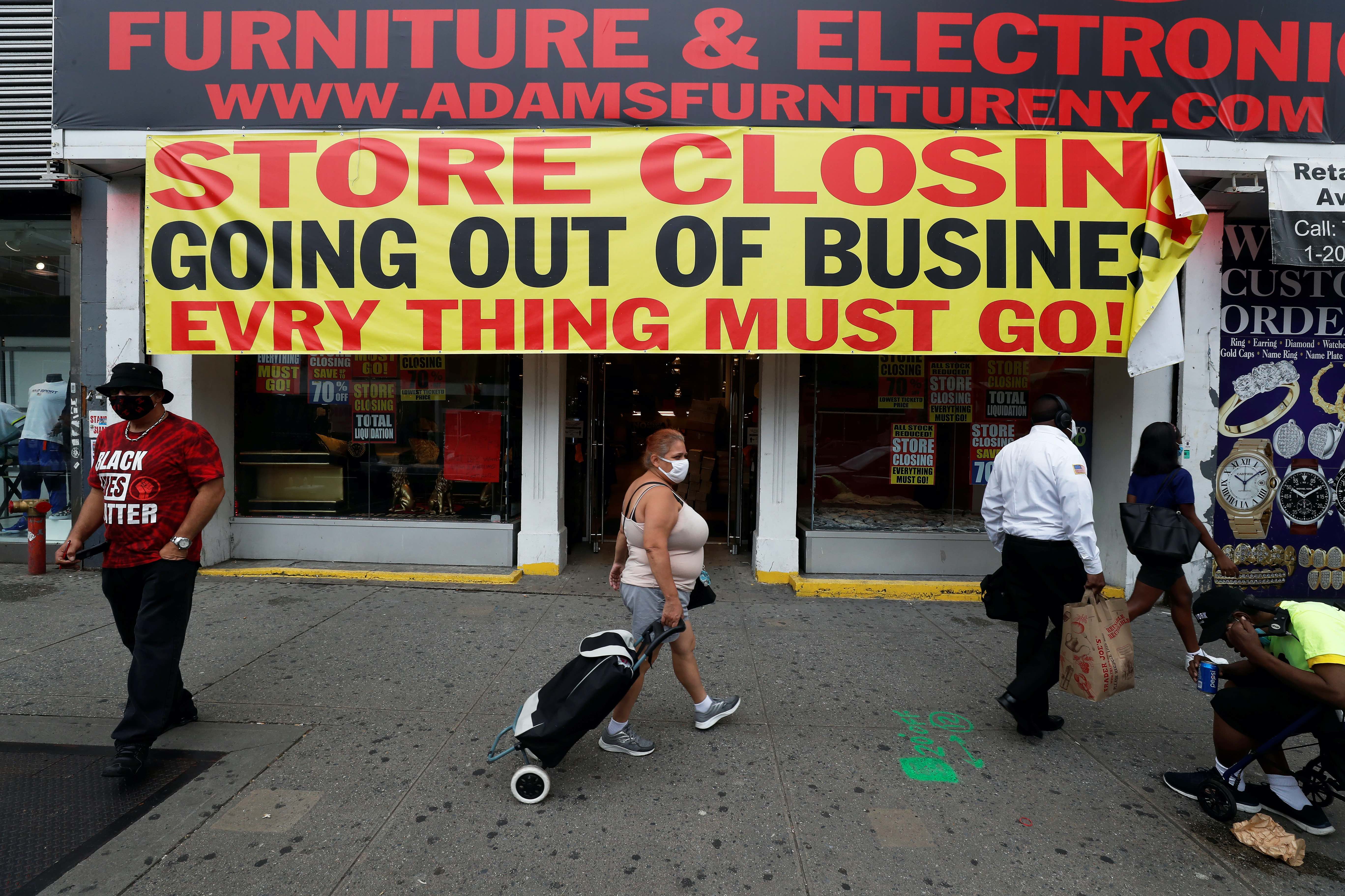 People walk by a store going out of business along 125th Street in the Harlem neighbourhood of New York City, New York, the United States
