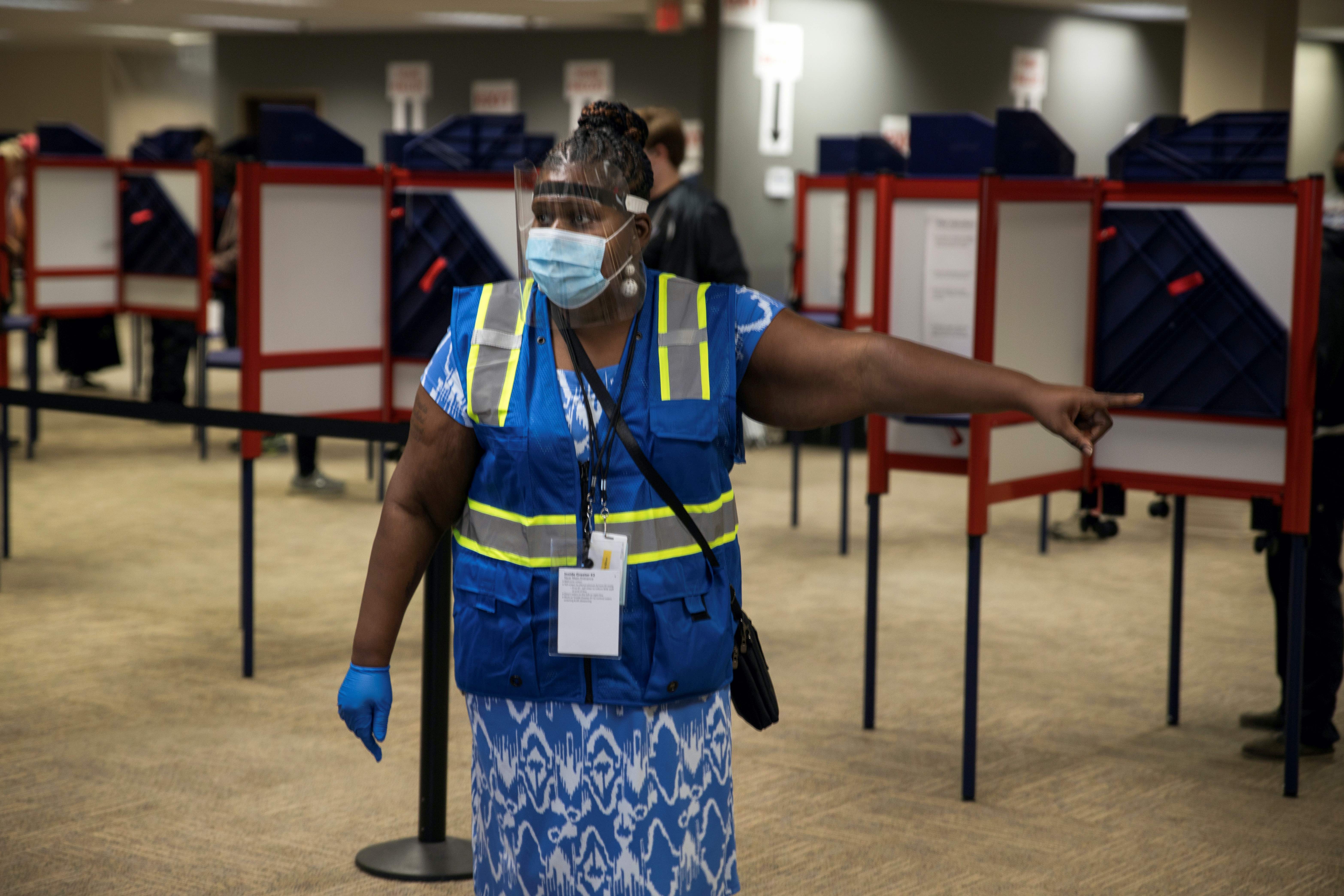 A poll worker directs voters to cast their ballots for the upcoming presidential election as early voting begins in Cincinnati, Ohio, US, October 6, 2020