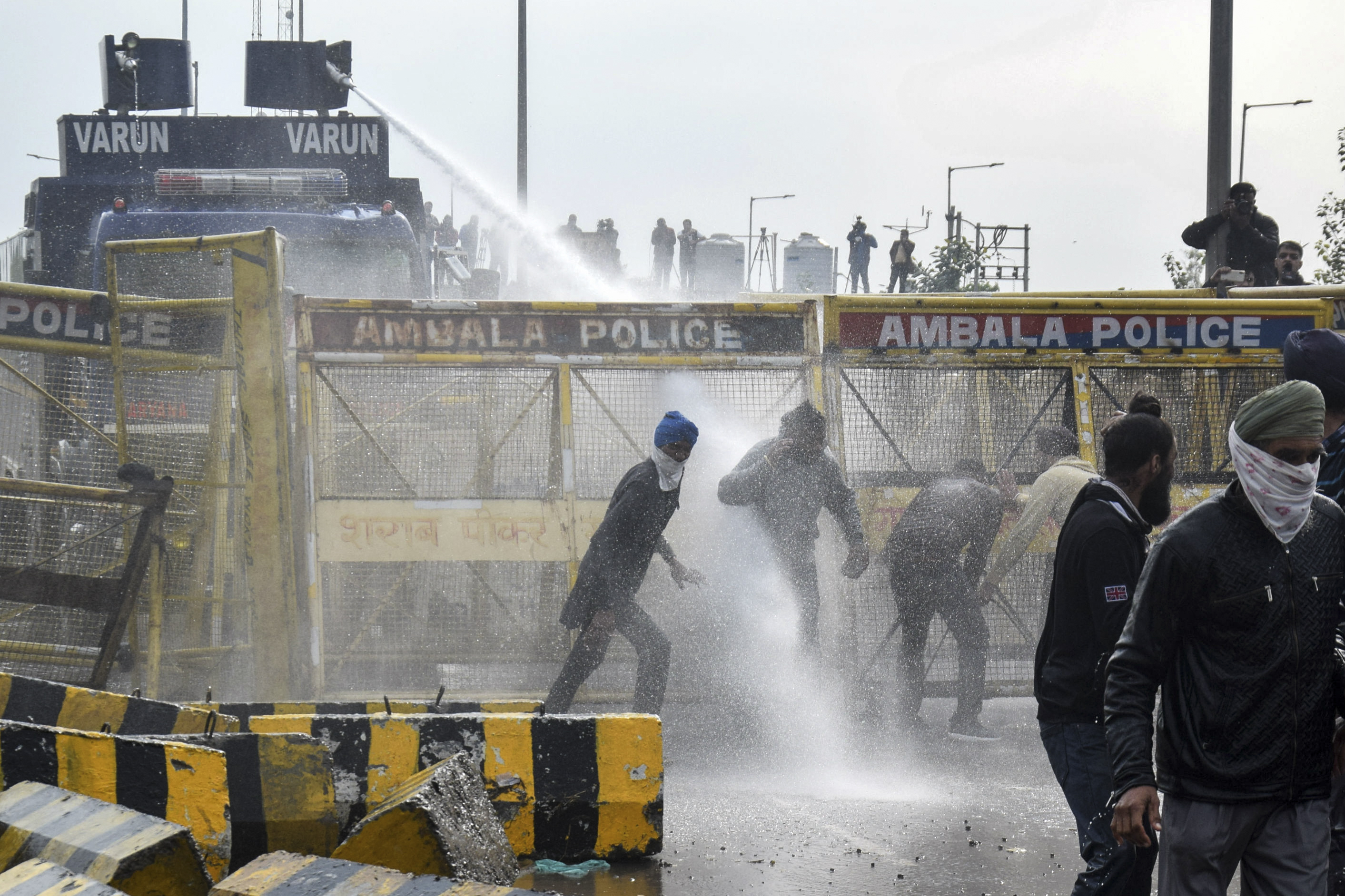 Police block a road and use a water cannon to disperse farmers [AFP]