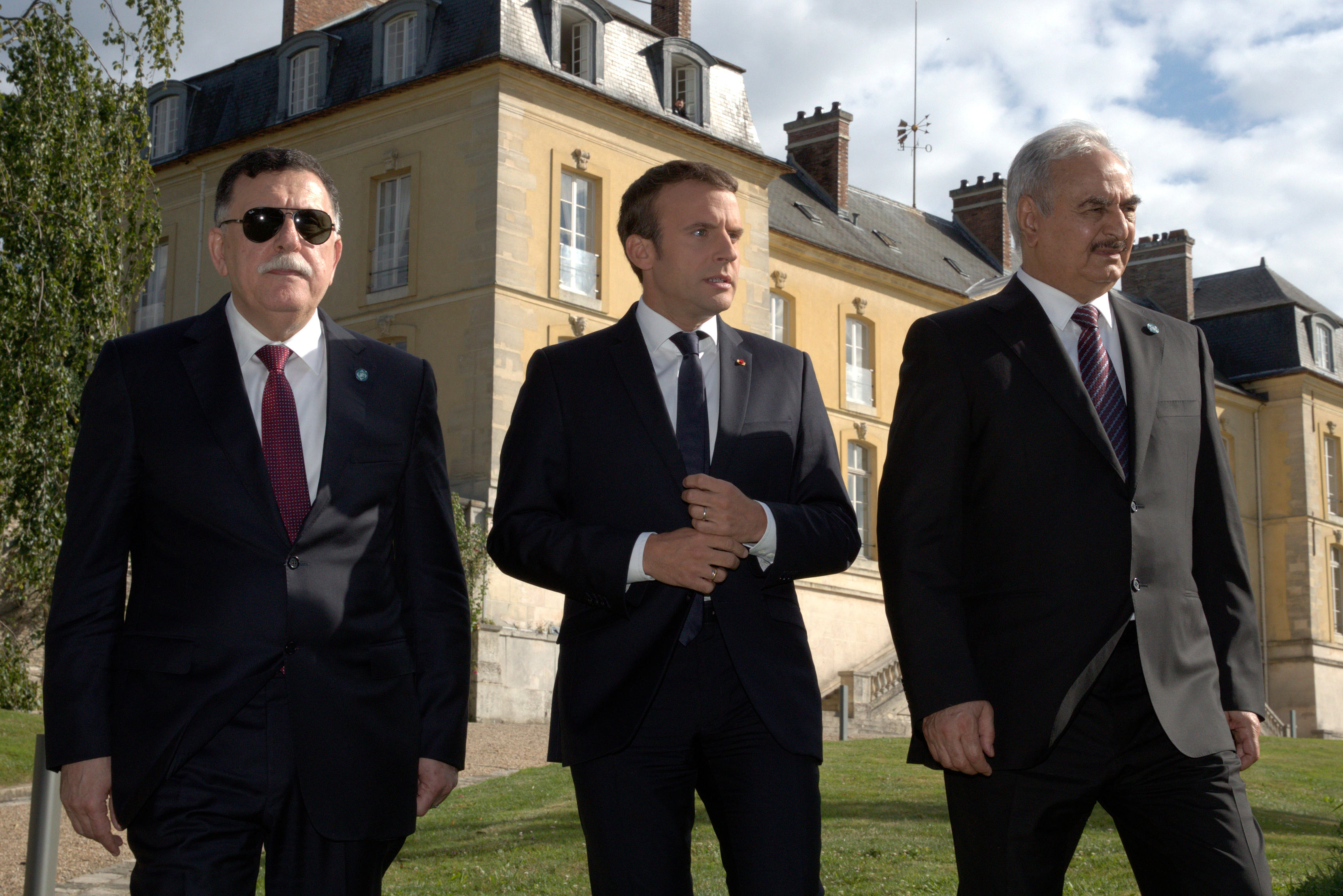 Macron walks with Libyan Prime Minister Fayez al-Sarraj, left, and General Khalifa Haftar, right, commander in the Libyan National Army (LNA), after talks about a political deal to help end Libya’s crisis in La Celle-Saint-Cloud near Paris, France, July 25, 2017