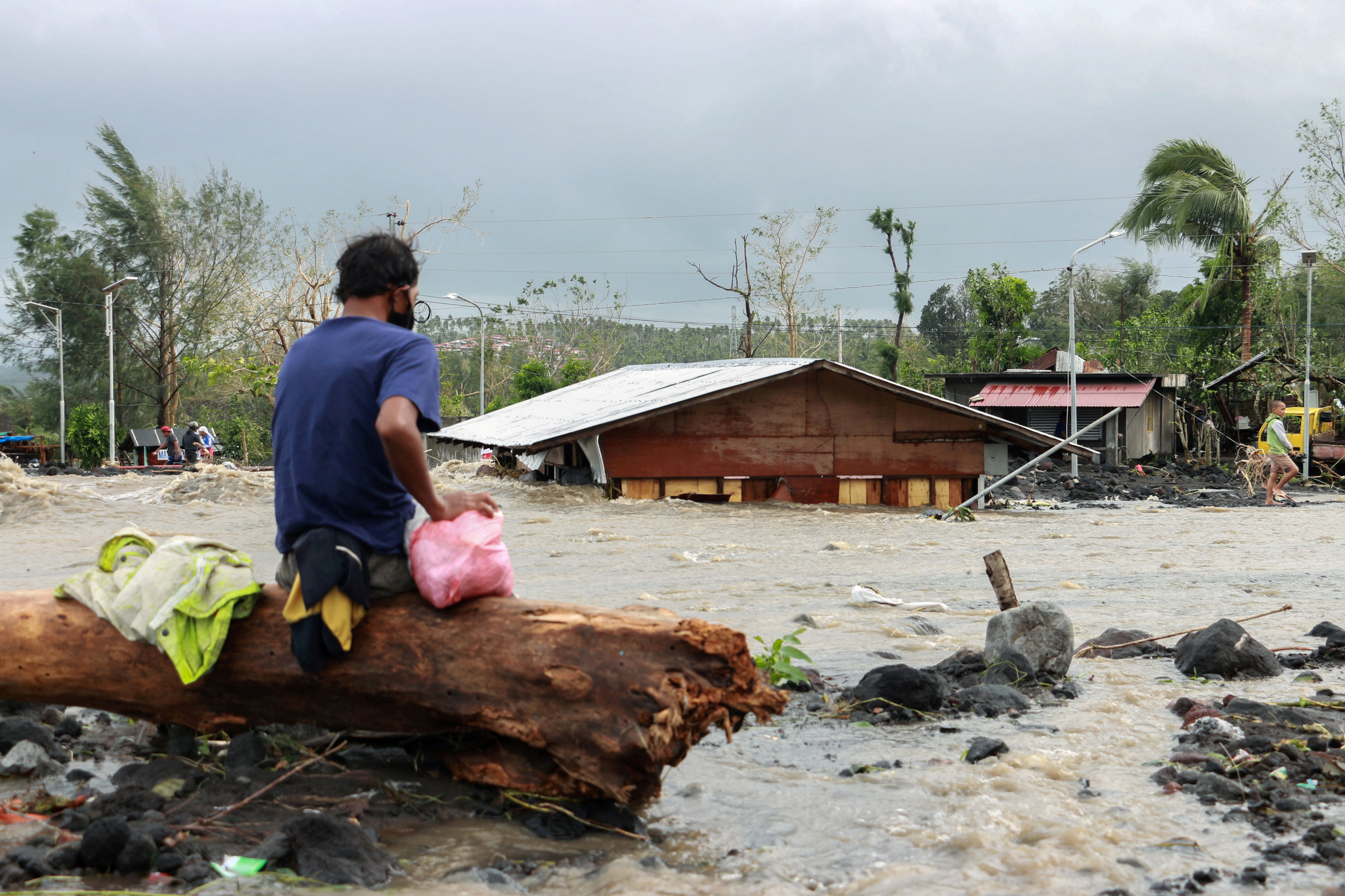 A man looks at his house across the swirling waters of a flash flood brought by Typhoon Goni in Barangay Busay, Daraga town, Albay province