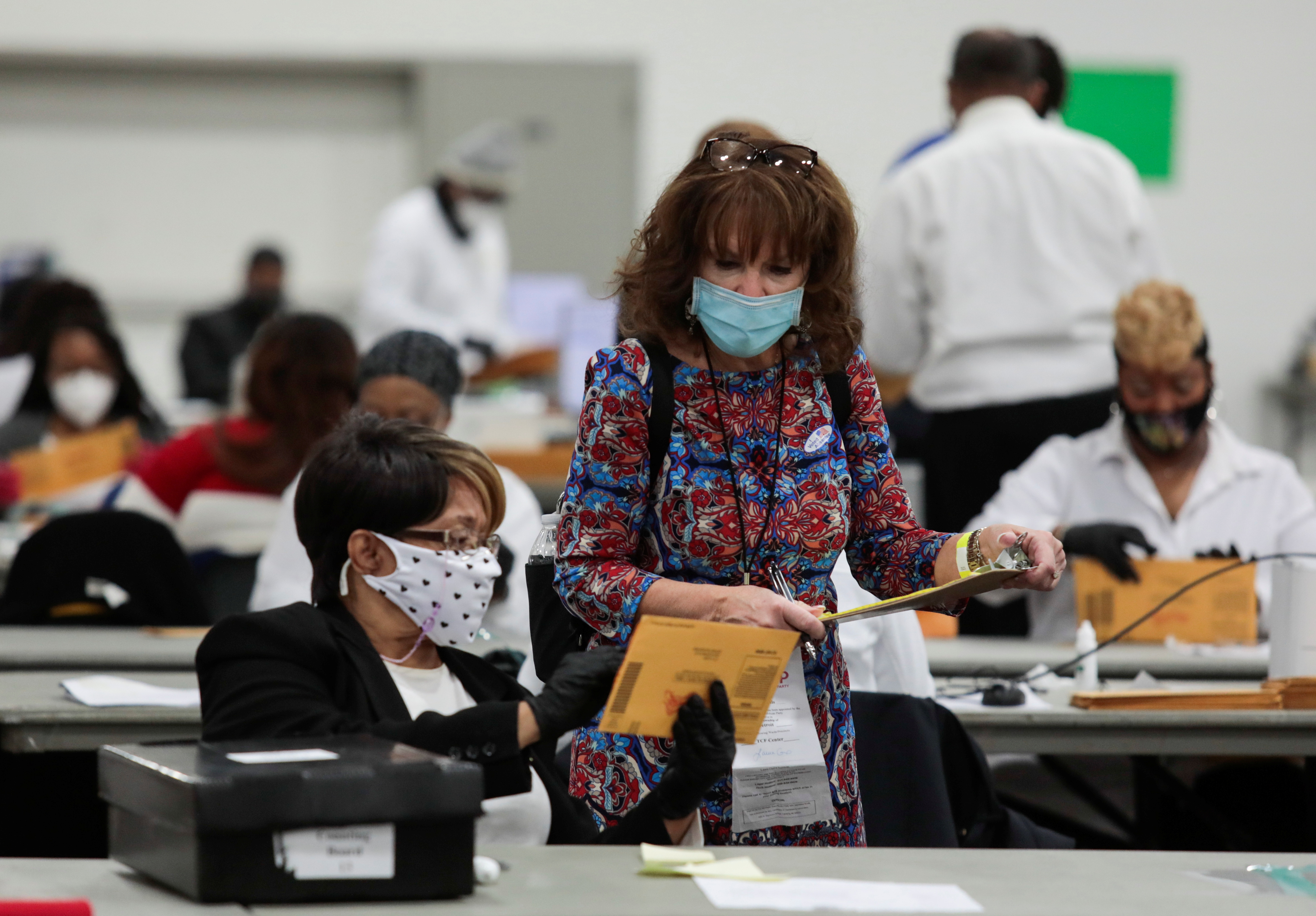 A poll challenger looks at absentee ballots to be counted on Election Day being processed by poll workers, at the TCF Center in Detroit, Michigan, on November 2