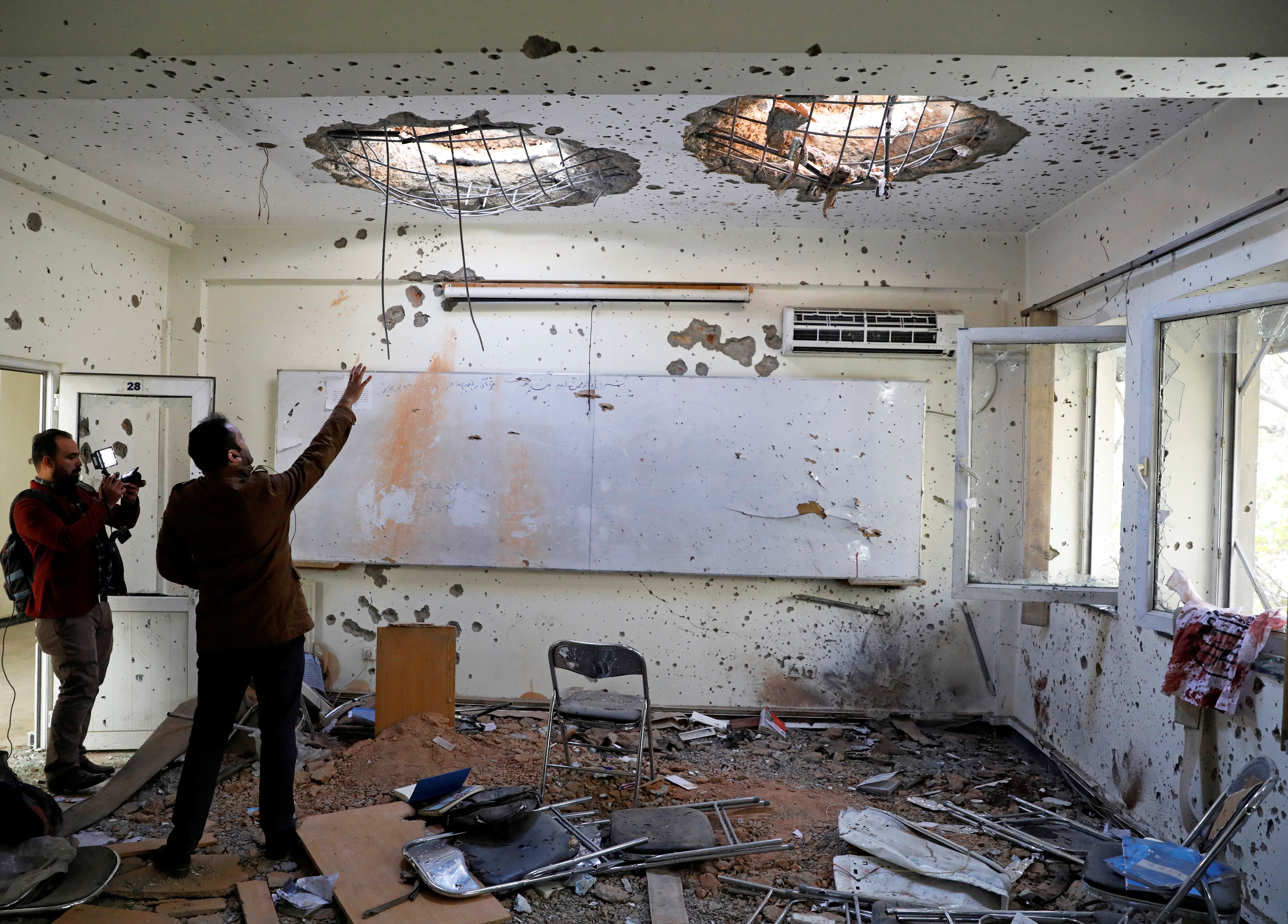 Afghan journalists film inside a classroom after the attack at the Kabul University, Afghanistan, where 22 students were killed earlier this week