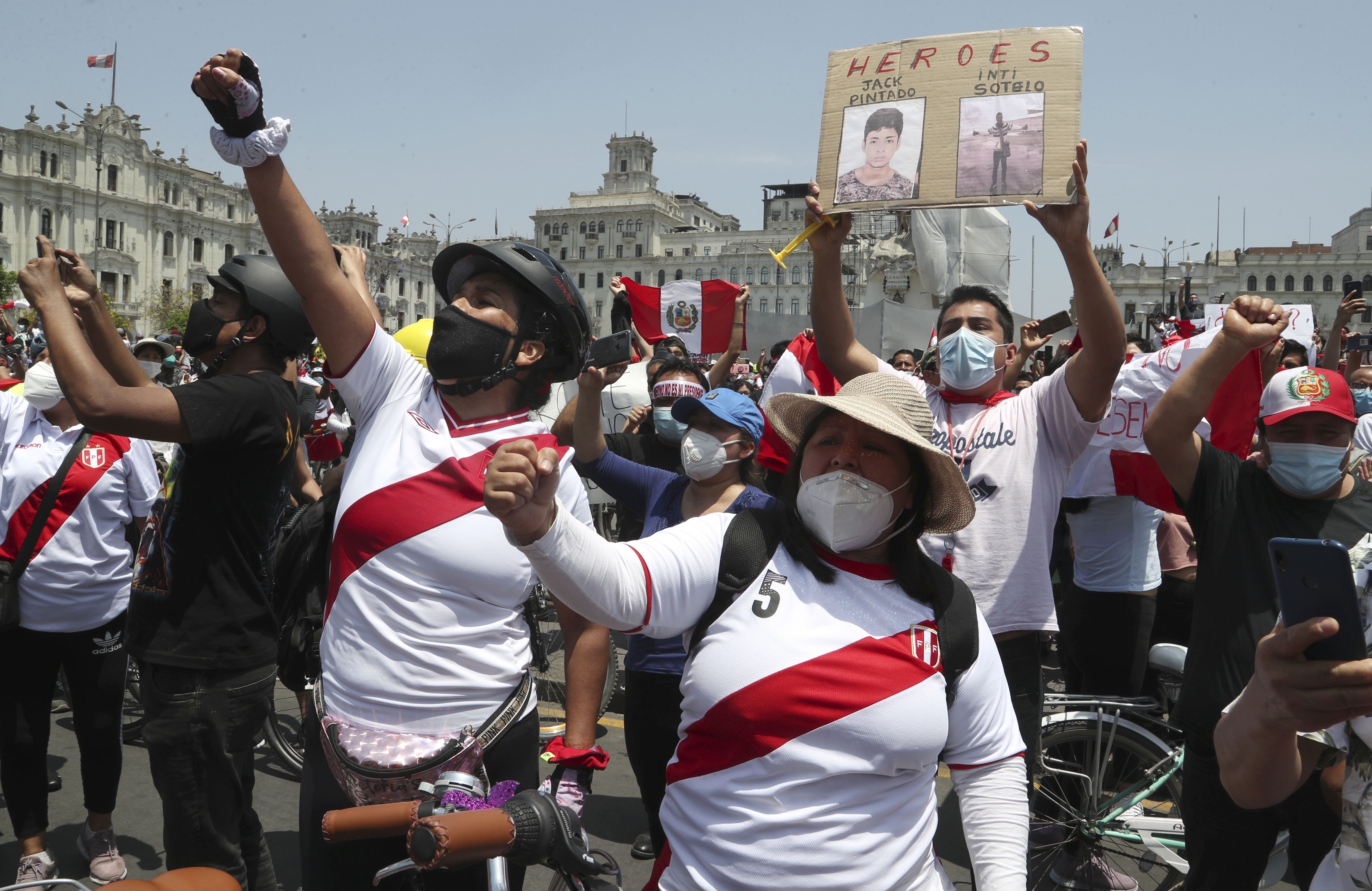A person holds a sign with photos of two demonstrators killed during protests as people celebrate the resignation of interim President Manuel Merino in Lima, Peru