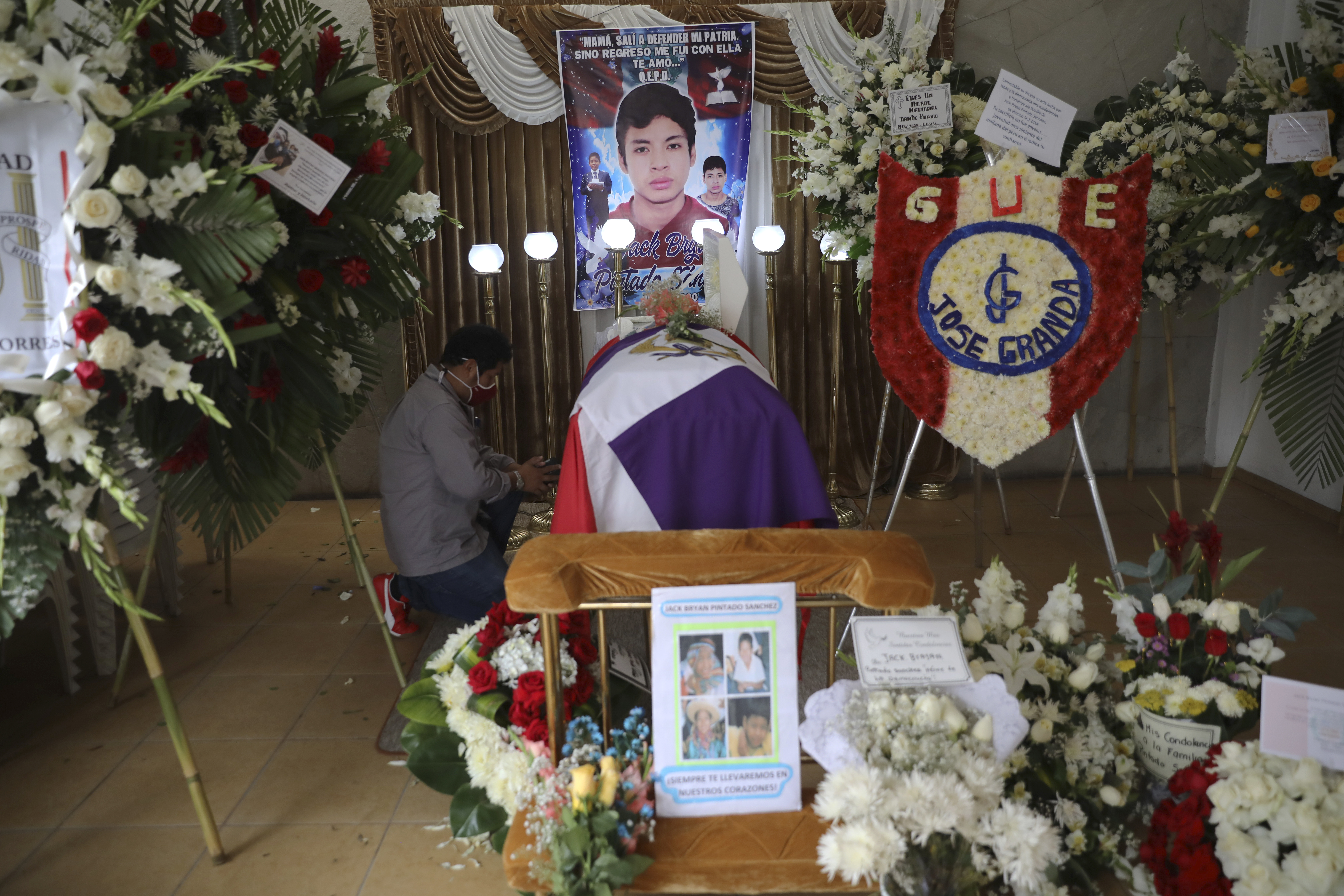 A man kneels by the coffin of Jack Bryan Pintado Sanchez, a 22-year-old who died during weekend protests against legislators’ removal of President Martin Vizcarra, at a church during his wake in Lima, Peru