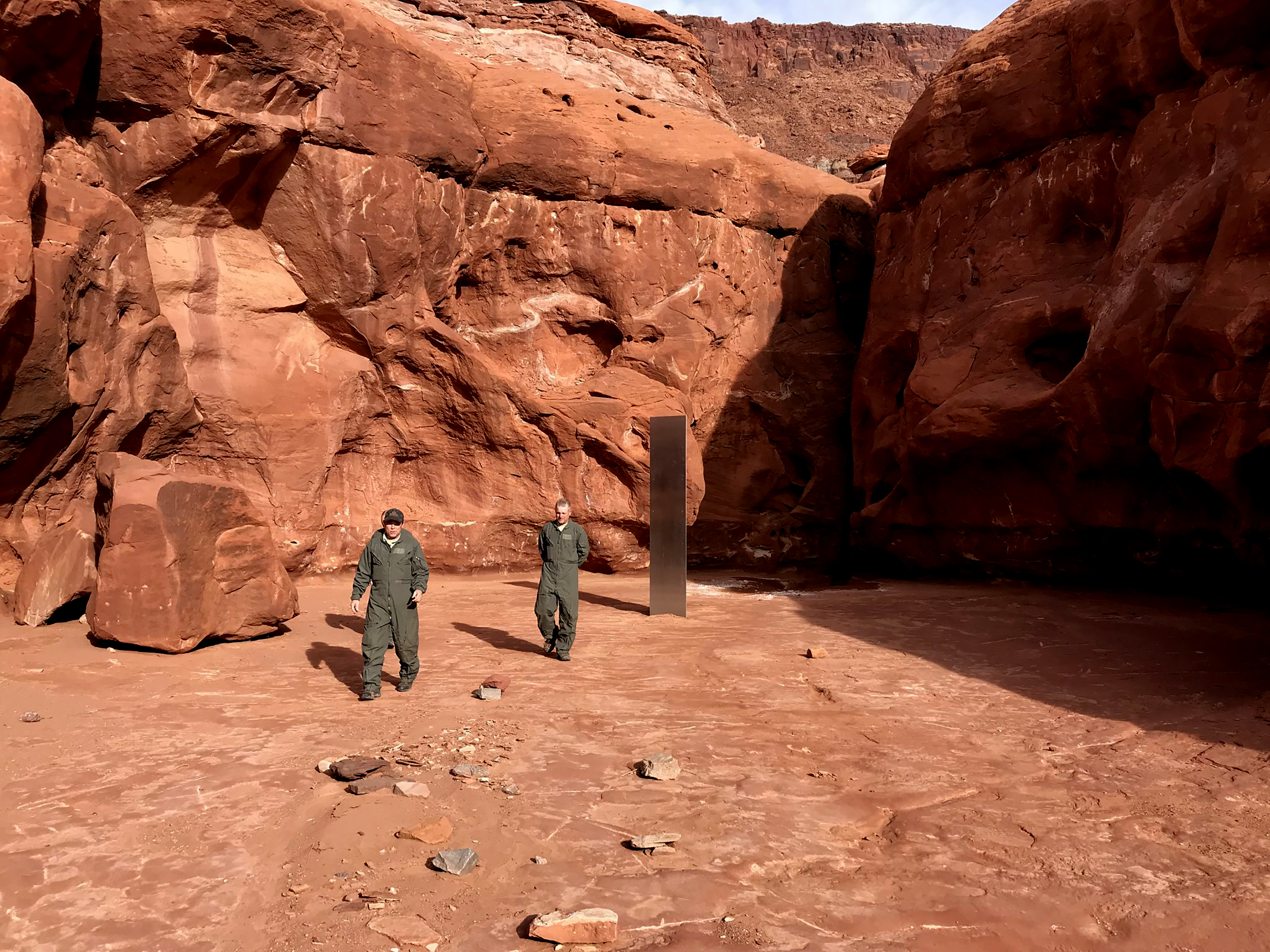 Utah state workers walking near a metal monolith in the ground in a remote area of red rock in Utah [Utah Department of Public Safety via AP Photo]