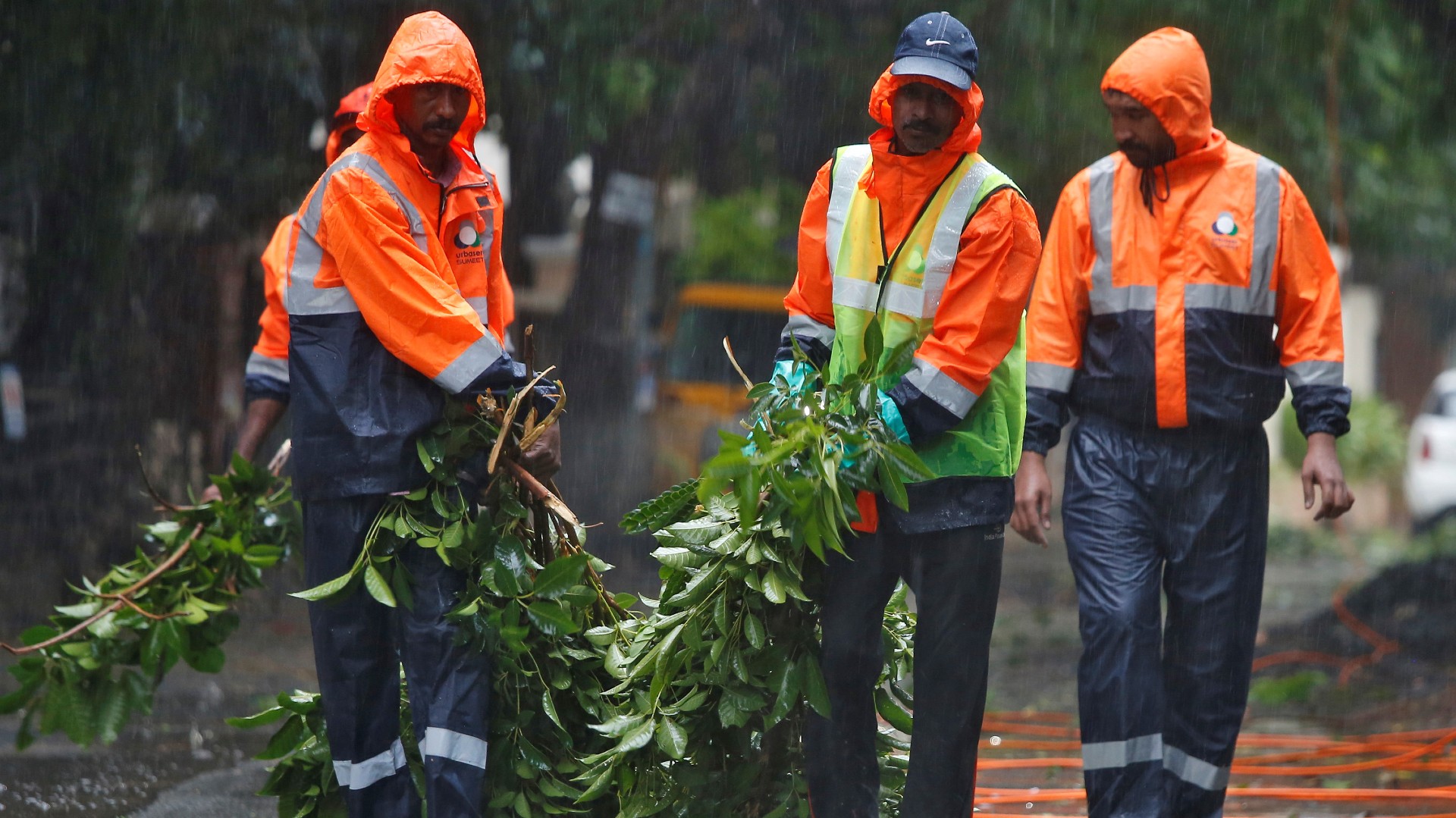 Municipal workers remove fallen tree branches from a road during rains before Cyclone Nivar’s landfall in Chennai