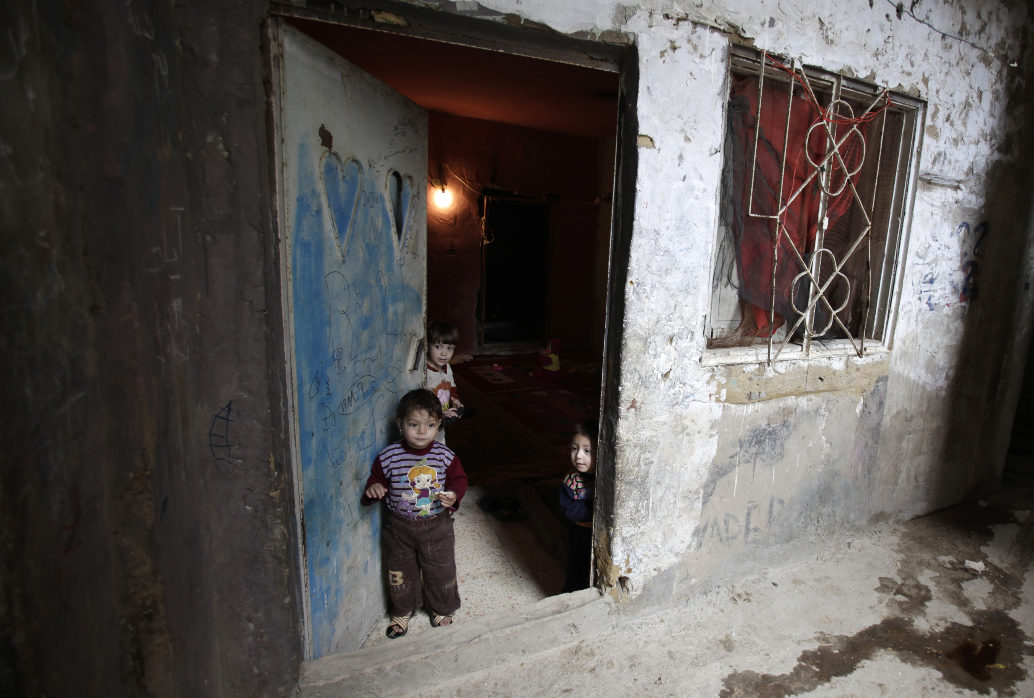 Palestinian children look out of the door of their house in Shatila refugee camp in Beirut on March 3, 2010. The camp was set up by UNRWA in 1949