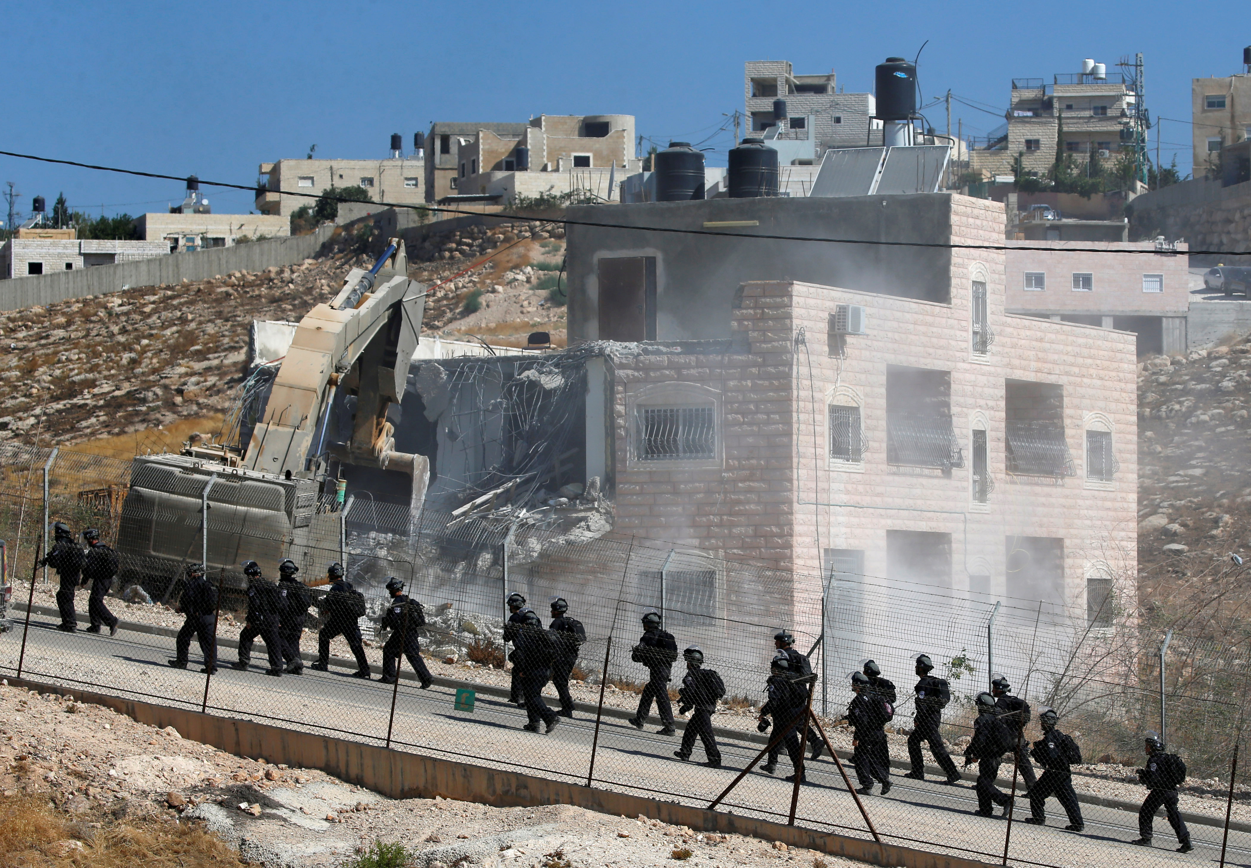 Israeli forces patrol as a Palestinian building in demolished in the village of Sur Baher, which sits on either side of the Israeli barrier in occupied East Jerusalem and the occupied West Bank