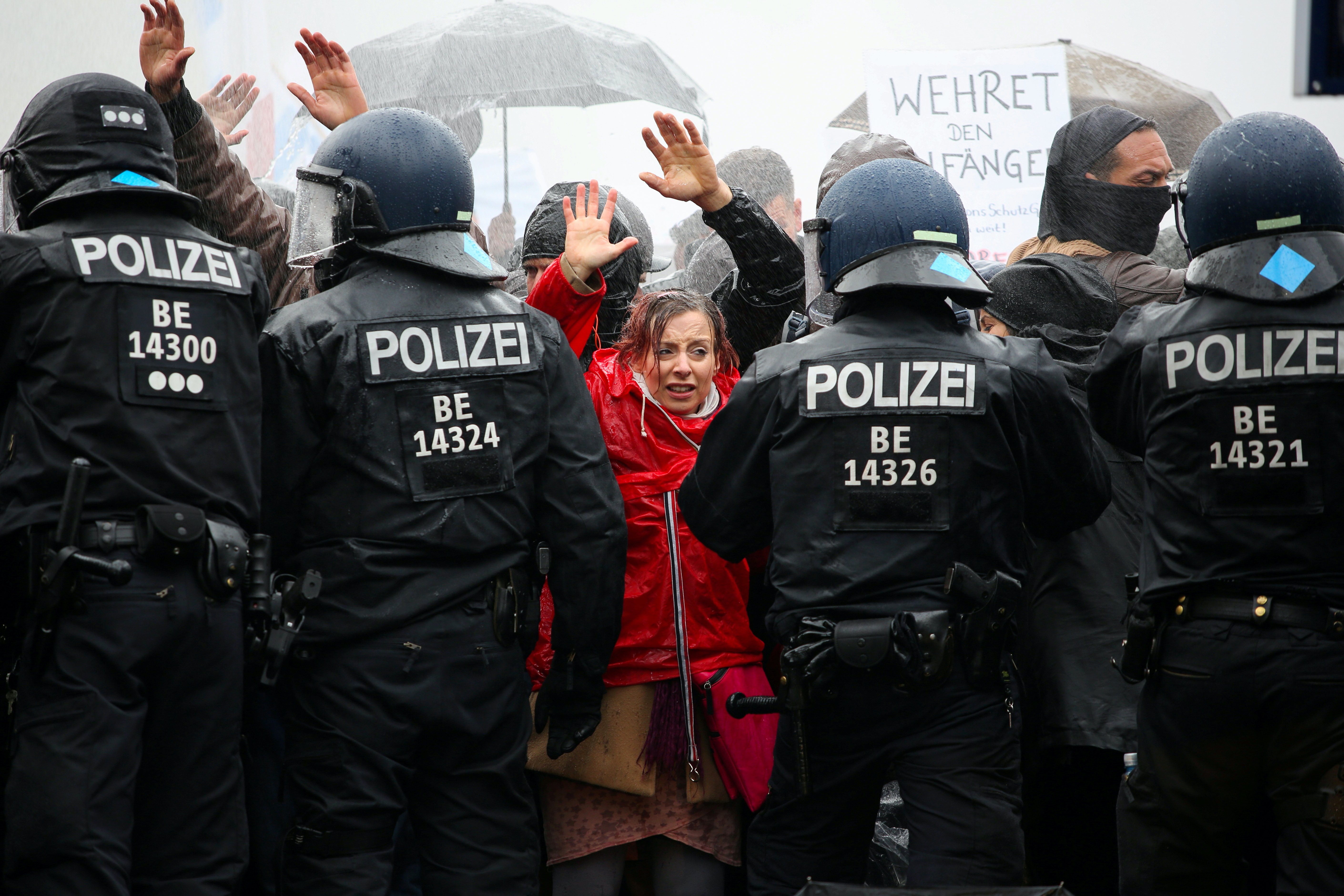 Demonstrators put up their hands in front of police officers during a protest against the government’s coronavirus restrictions, near the Brandenburger Gate in Berlin, Germany